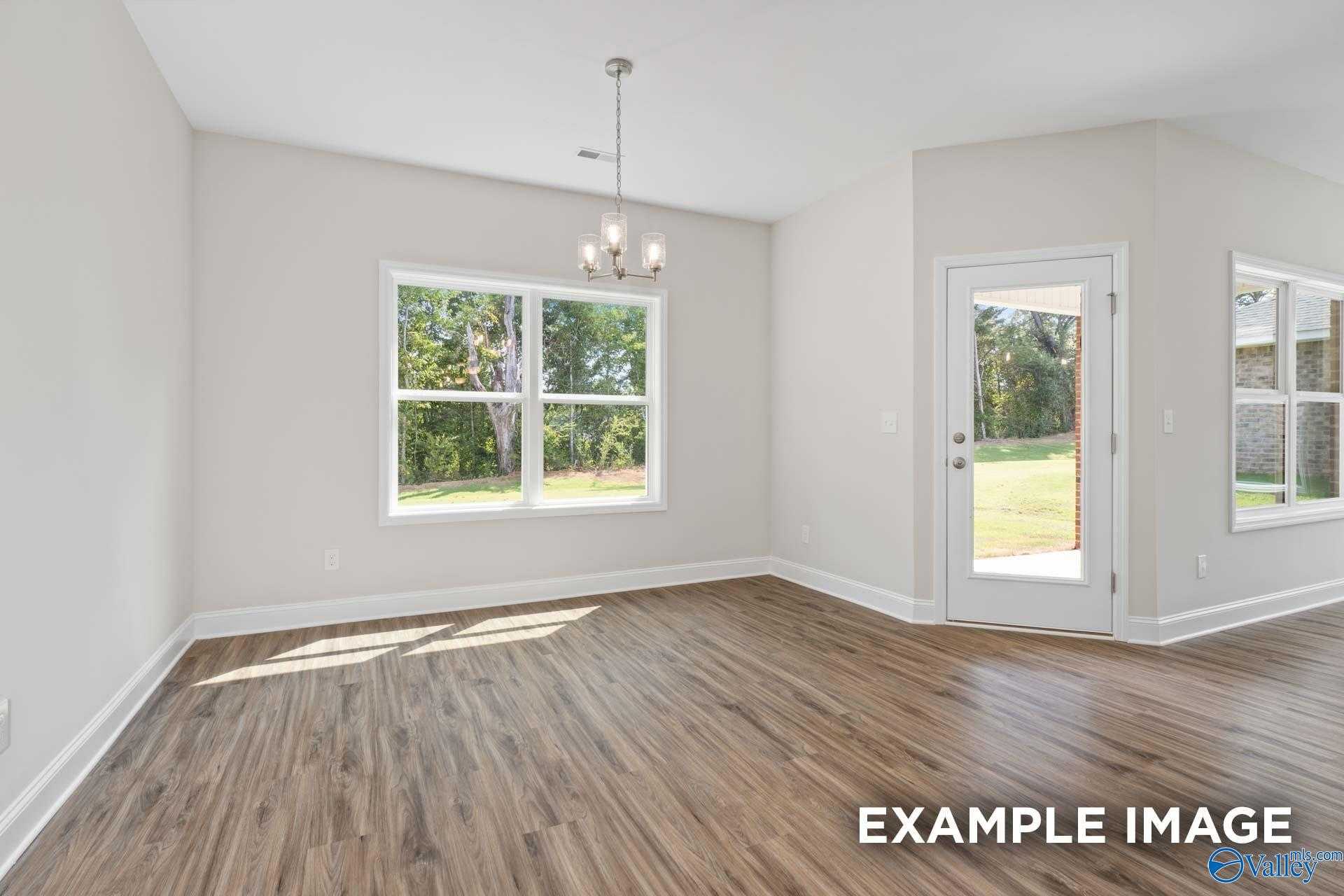 Bright dining room with hardwood floors, chandelier, large windows, and screen door to wooded backyard in Davidson Homes The Franklin, Meridianville, Alabama