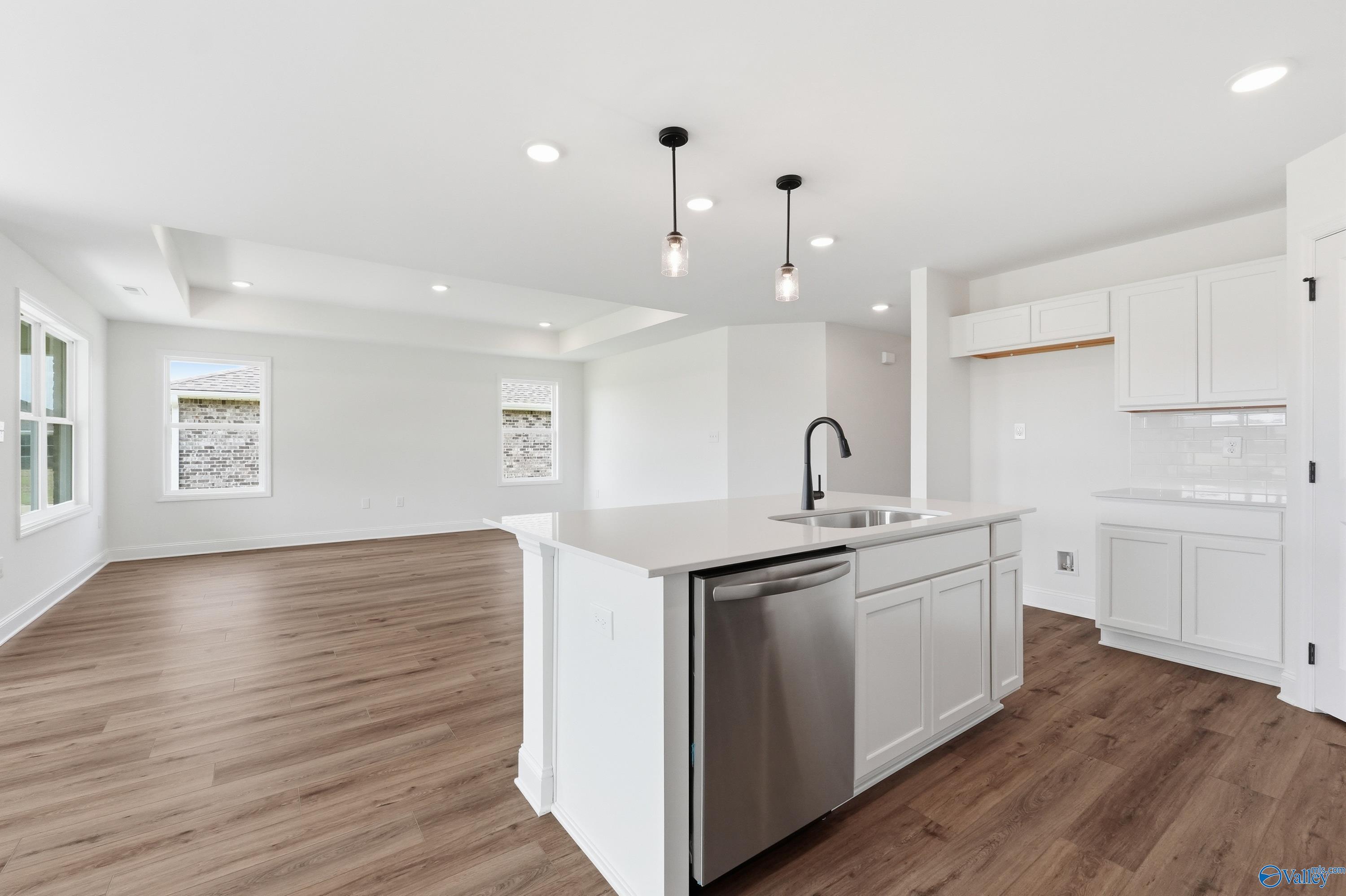 Open-concept white kitchen with island and wood-style flooring in The Franklin floor plan at Heritage Lakes, New Market.