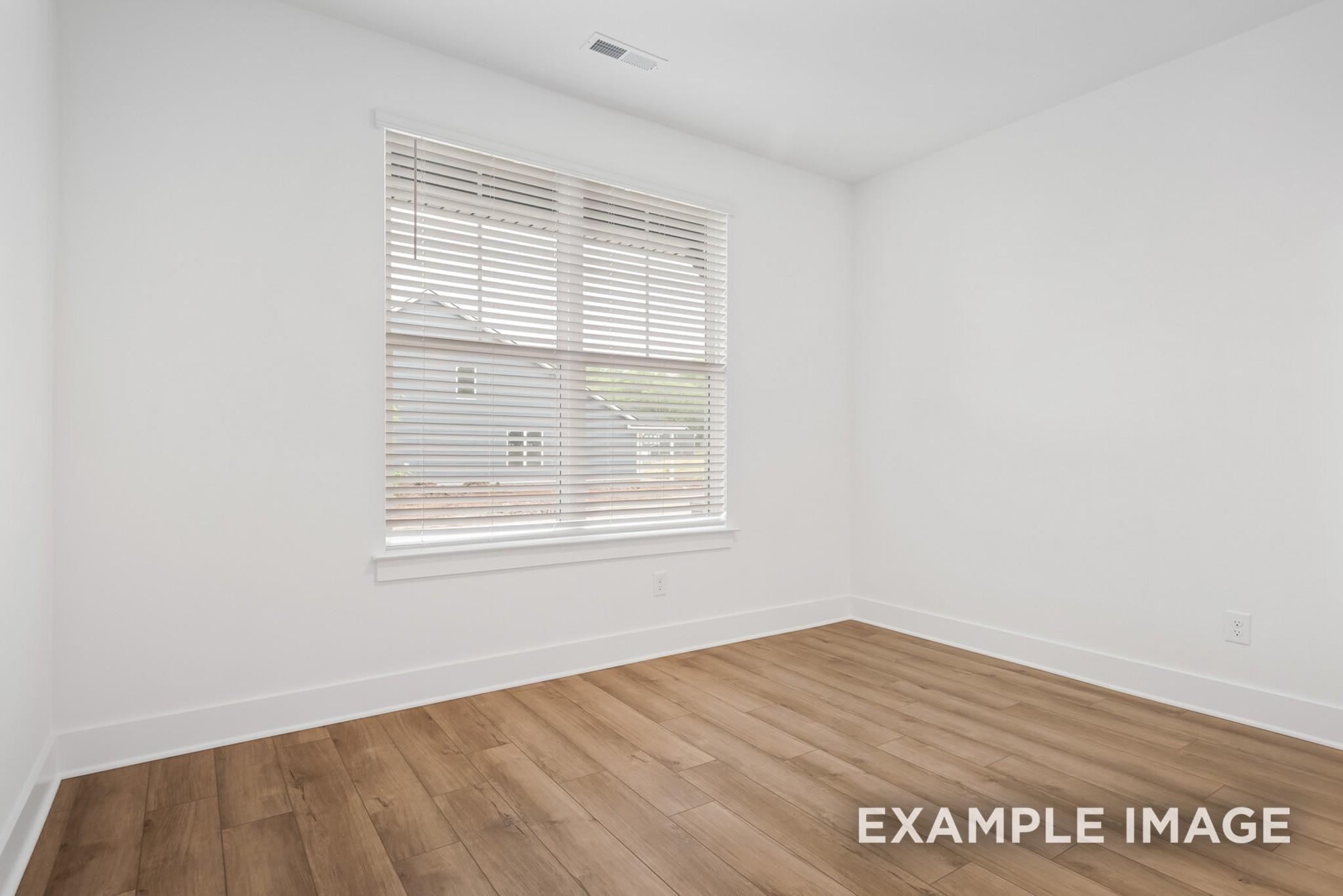 Bright empty bedroom with hardwood floors, white walls, and large window blinds in Davidson Homes The Ridgeport C, Gallatin, TN