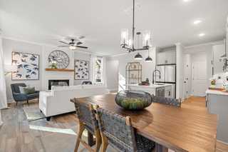 Open-concept living and dining in The Washington H townhome, featuring fireplace, white sofa, wood table, and modern kitchen island