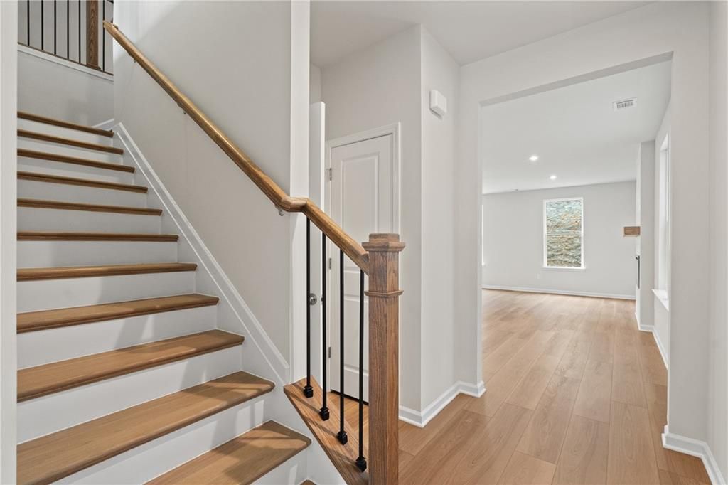 Elegant oak staircase with wrought iron railing in open foyer of The Marion B 2-story home by Davidson Homes, Kennesaw, GA
