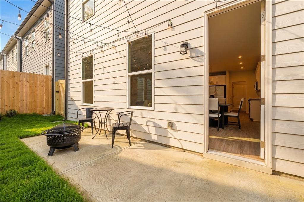 Cozy backyard patio with fire pit, bistro set, string lights, and open kitchen door in Davidson Homes The Marion B, Kennesaw, Georgia