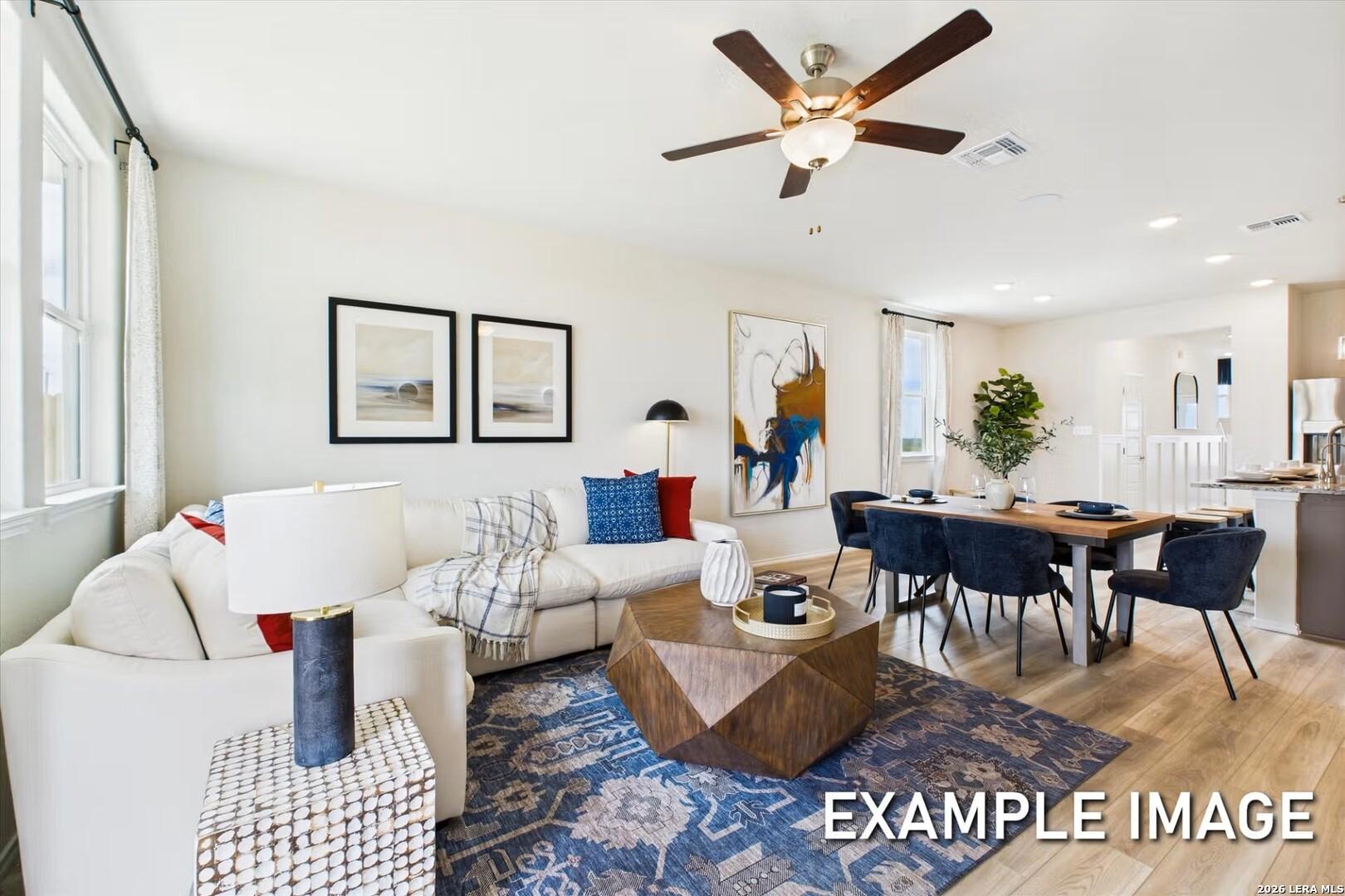 Cozy open living and dining area with white sectional sofa, wooden coffee table, blue rug, velvet chairs, in 5-bedroom Brazos B home, San Antonio, Texas