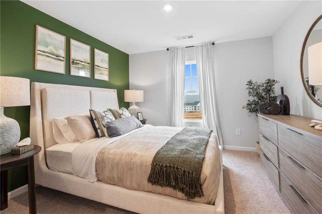Cozy bedroom with green accent wall, abstract art, king bed, and scenic window view in Davidson Homes The Wilmington B, Emerson, Georgia