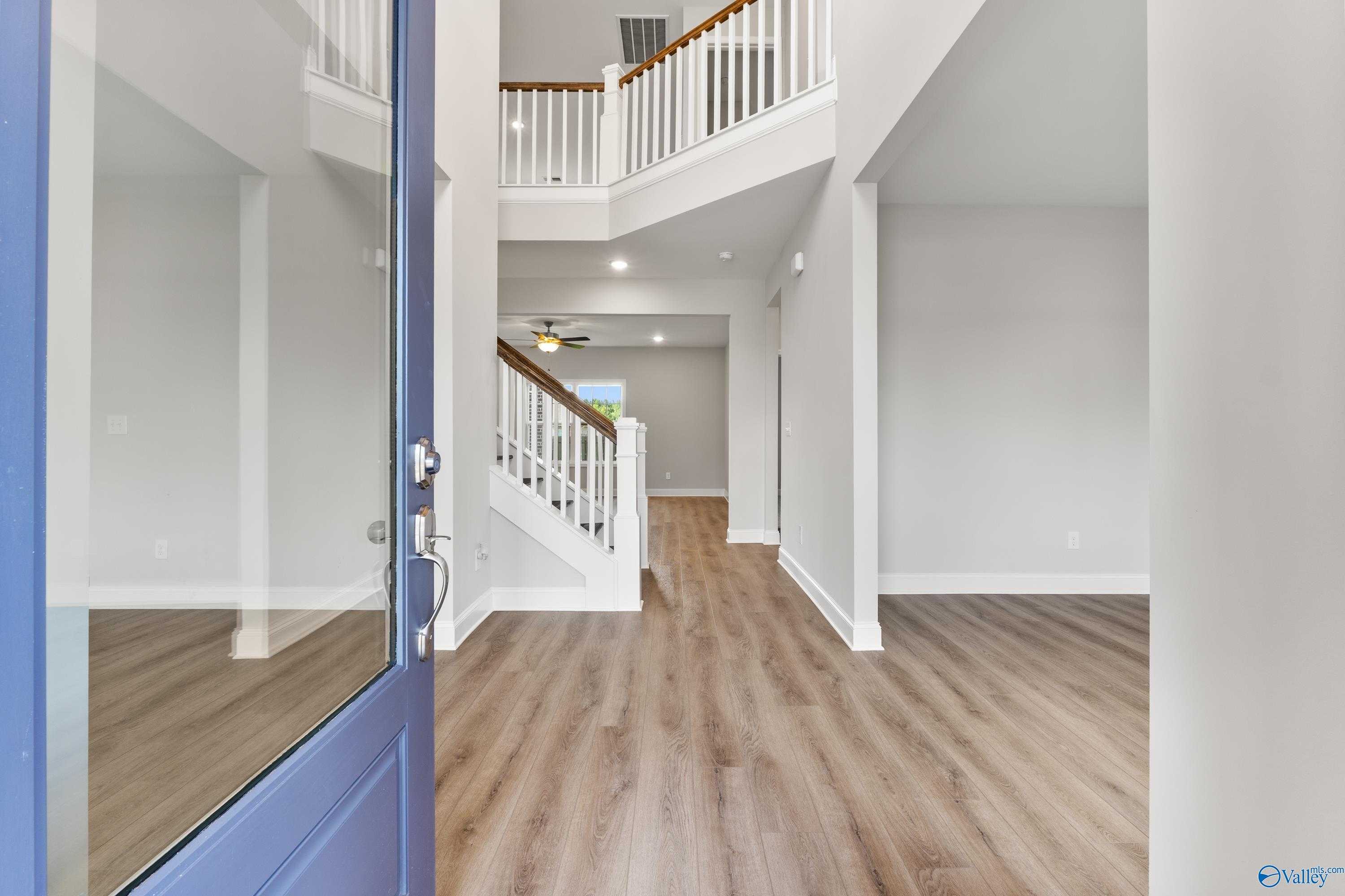 Grand two-story foyer with wooden staircase, white railings, and hardwood floors in Davidson Homes The Madison A, Toney, AL