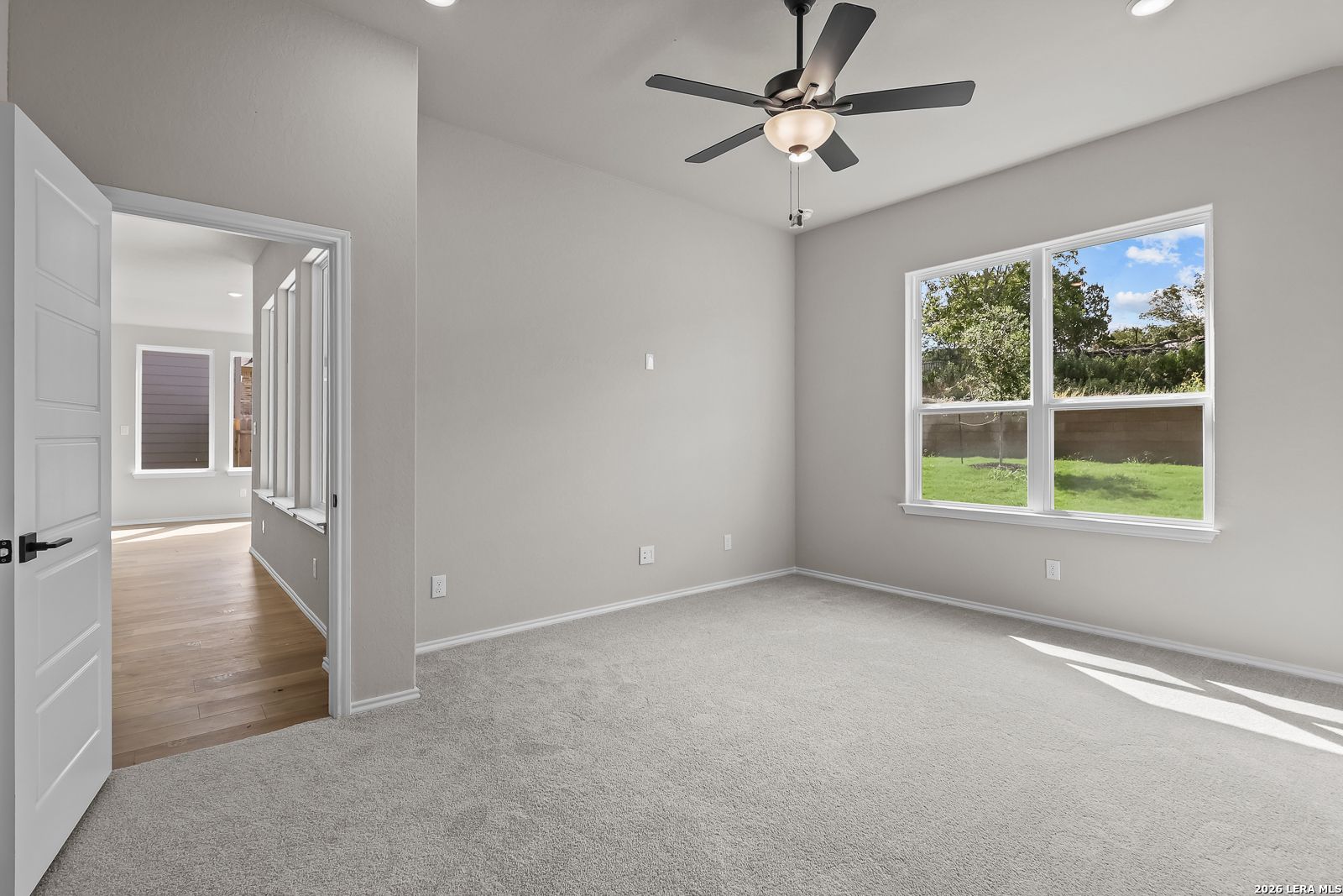 Bright carpeted bedroom with ceiling fan and backyard window in Davidson Homes' The Sequoia C, Royal Crest, San Antonio, TX