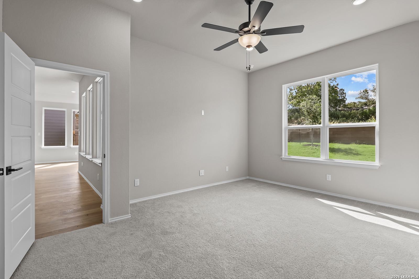 Bright carpeted bedroom with ceiling fan and backyard window in Davidson Homes' The Sequoia C, Royal Crest, San Antonio, TX