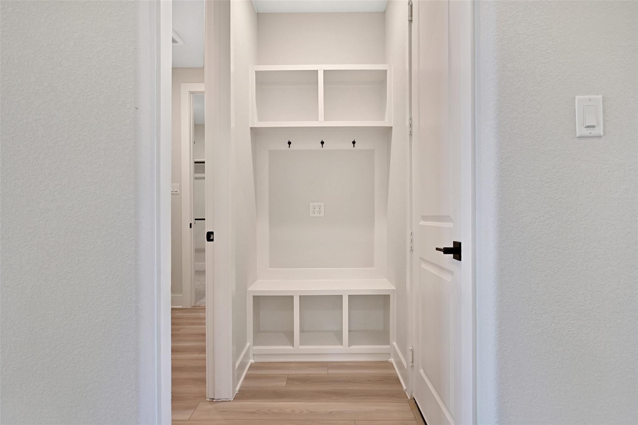 Built-in mudroom with white cabinetry, bench seat, coat hooks, and storage cubbies in Davidson Homes The Edward C, Lago Mar, Texas City