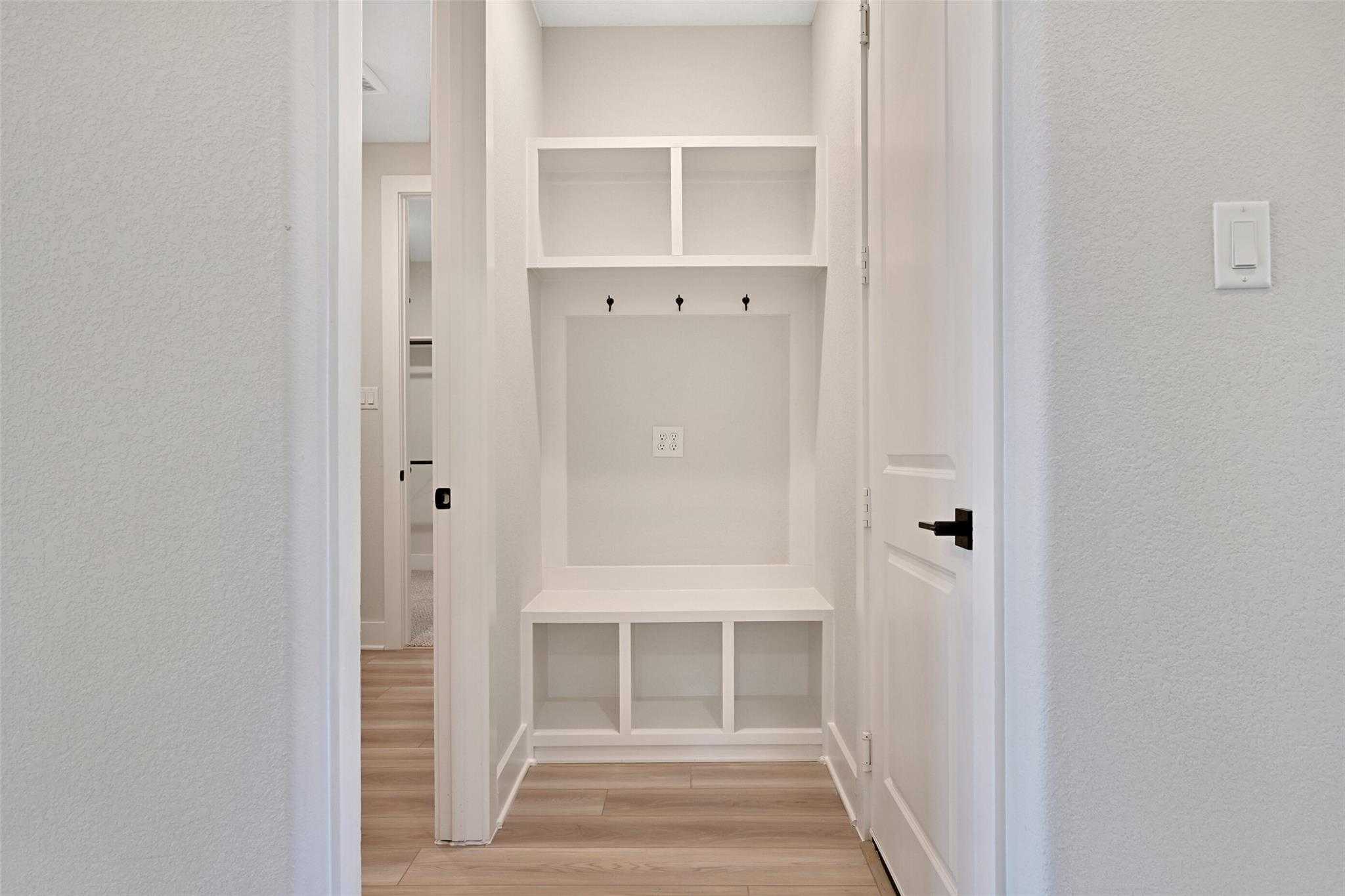 Built-in mudroom with white cabinetry, bench seat, coat hooks, and storage cubbies in Davidson Homes The Edward C, Lago Mar, Texas City