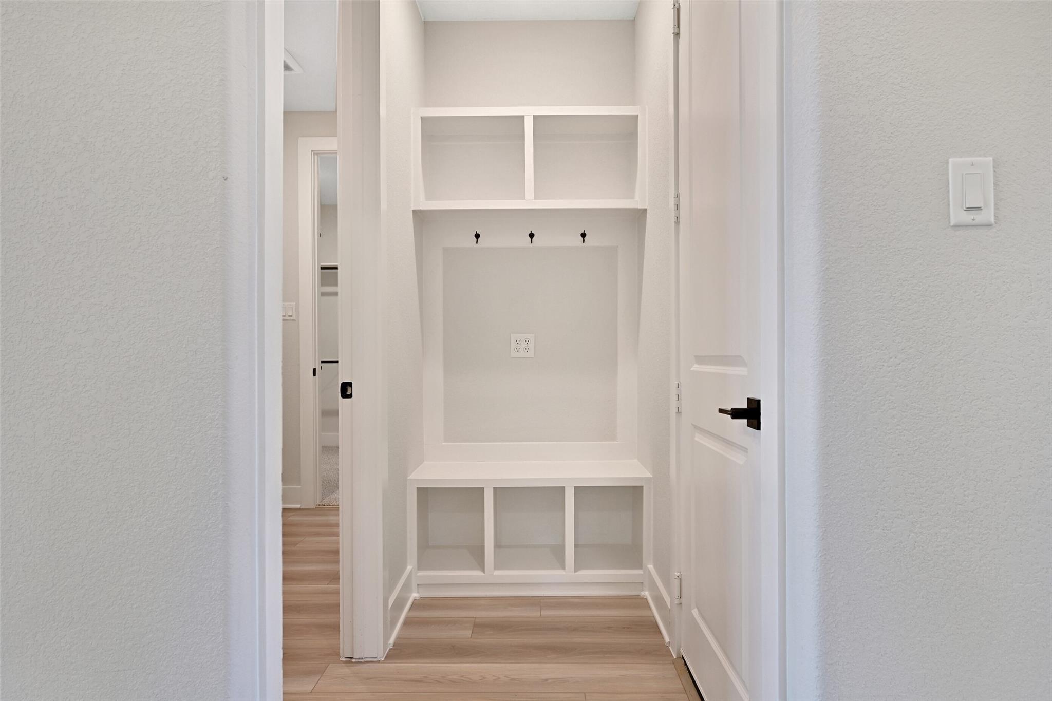 Built-in mudroom with white cabinetry, bench seat, coat hooks, and storage cubbies in Davidson Homes The Edward C, Lago Mar, Texas City