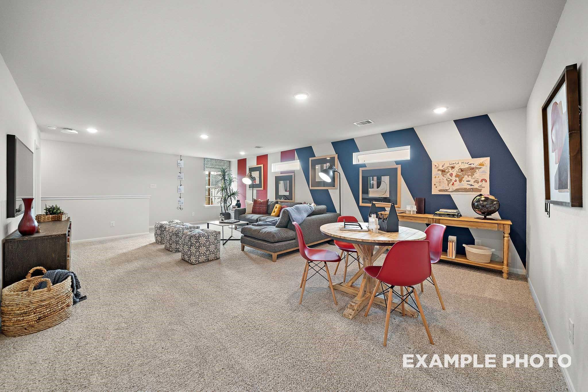 Stylish living room with striped accent wall, gray sofa, red chairs at round table, TV in Davidson Homes The San Marcos E, Conroe, Texas