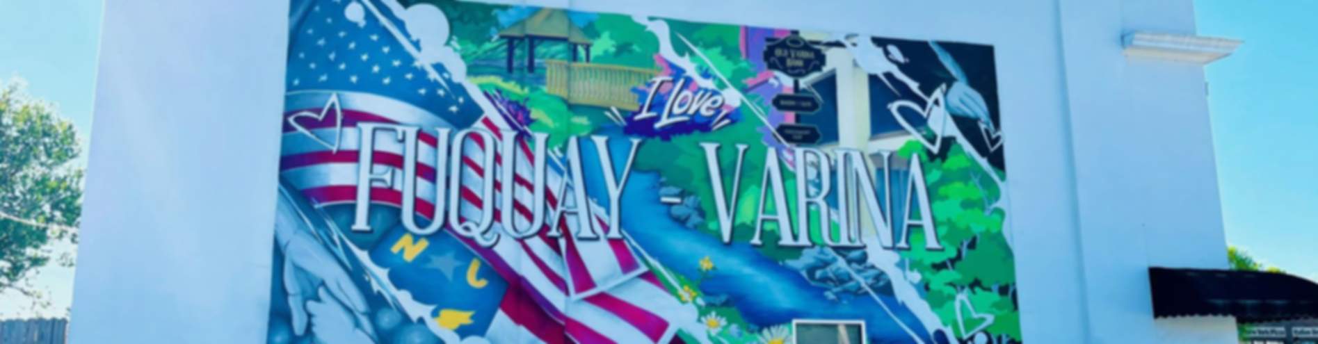 Vibrant mural on Fuquay-Varina building featuring "I Love Fuquay Varina" text with American flags, pagoda, and colorful motifs