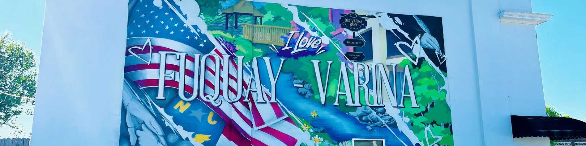 Vibrant mural on Fuquay-Varina building featuring "I Love Fuquay Varina" text with American flags, pagoda, and colorful motifs