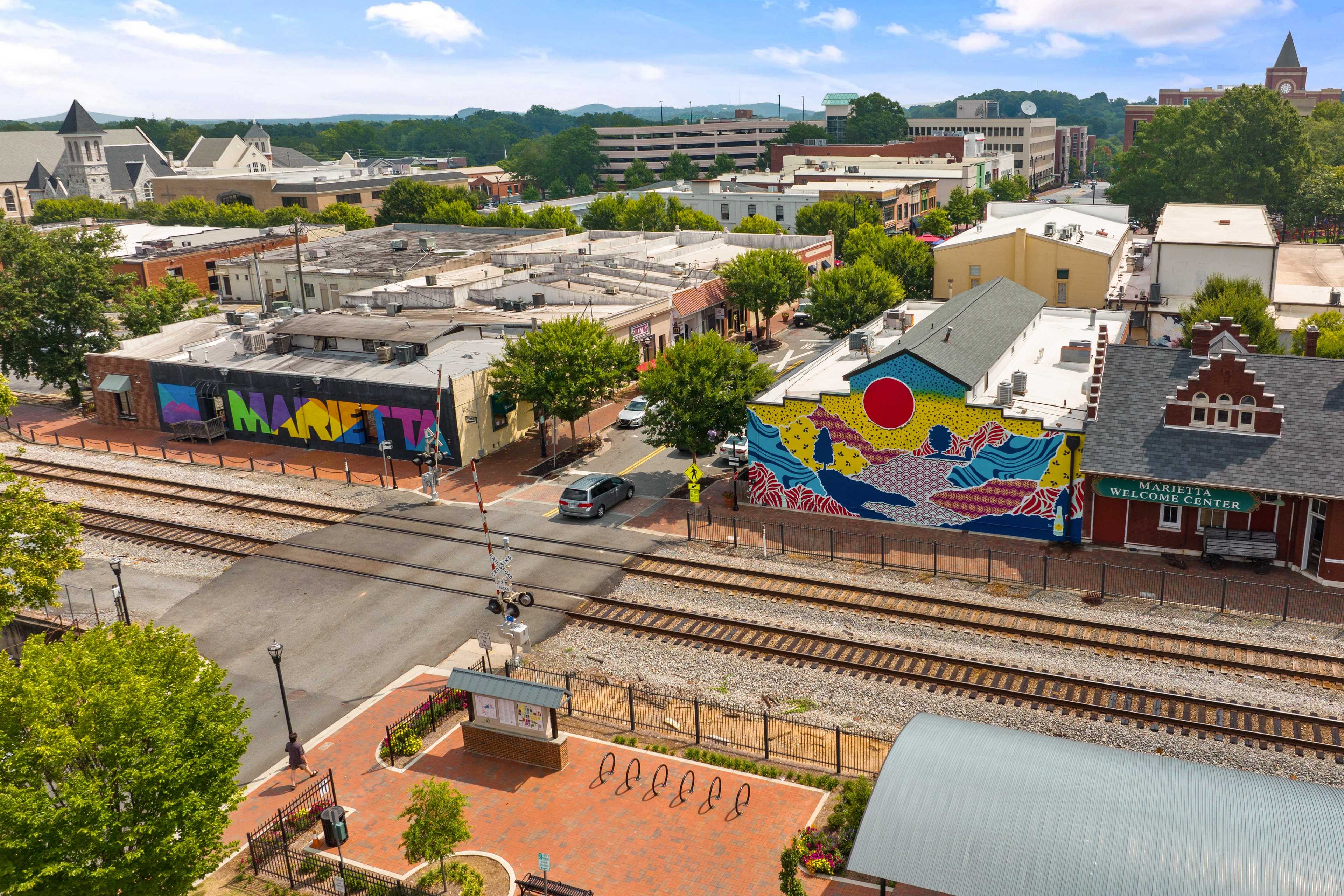 Vibrant street art mural on historic building with railroad tracks and urban greenery in Marietta GA Rosehill Townhomes