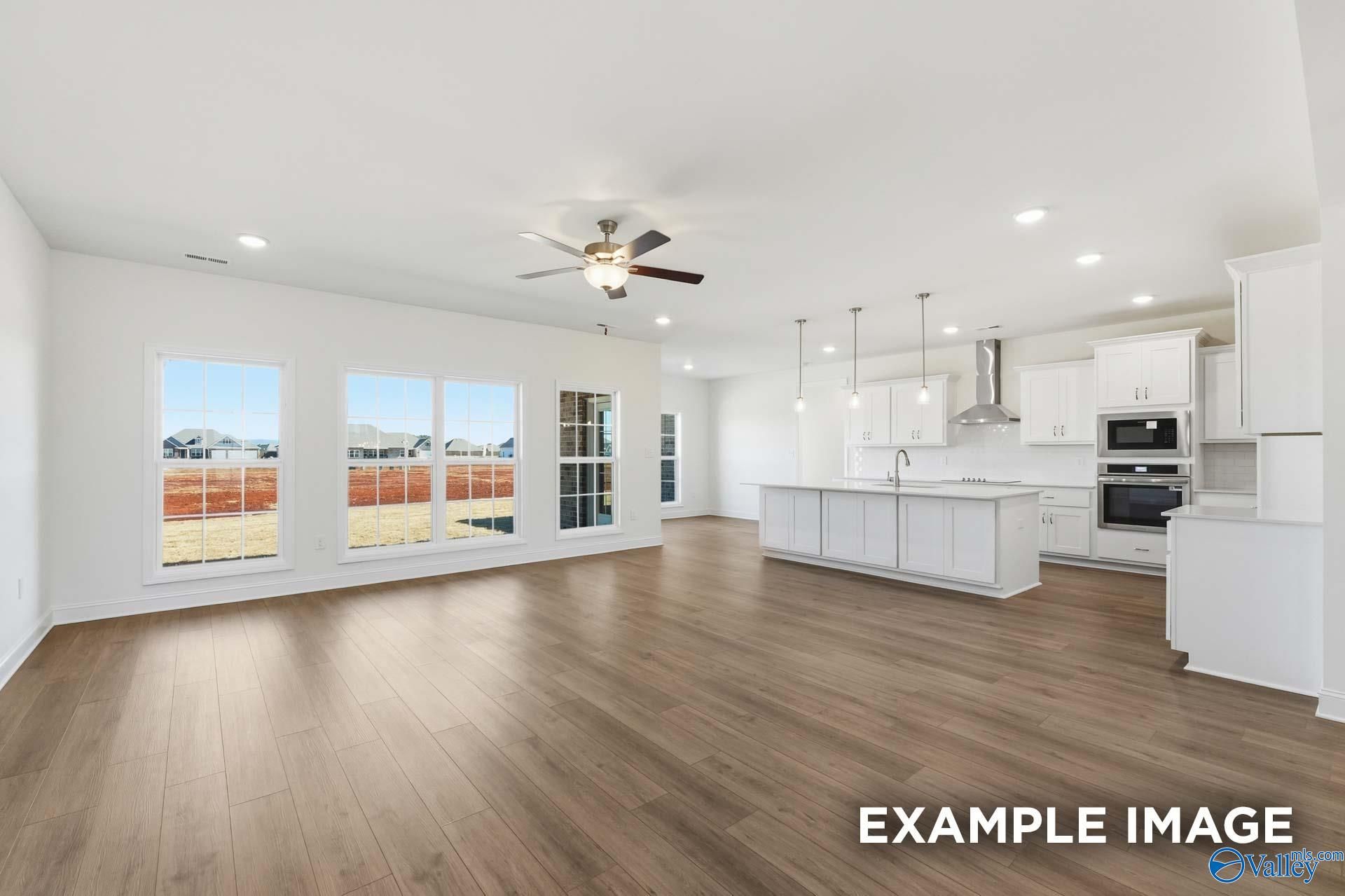 Open-concept living room and kitchen with white cabinets in The Valencia floor plan at Briercreek, Meridianville, Alabama.
