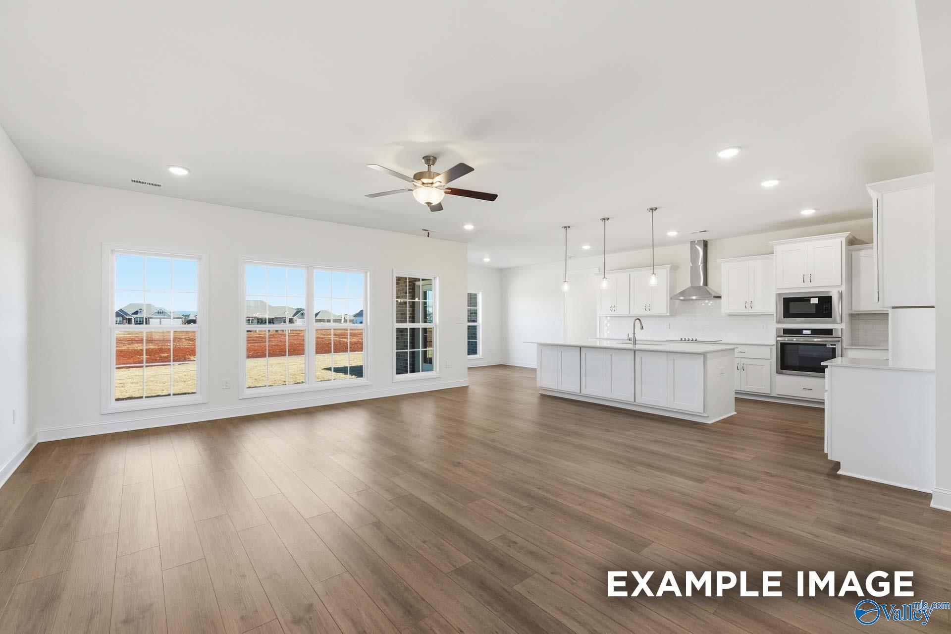 Open-concept living room and kitchen with white cabinets in The Valencia floor plan at Briercreek, Meridianville, Alabama.