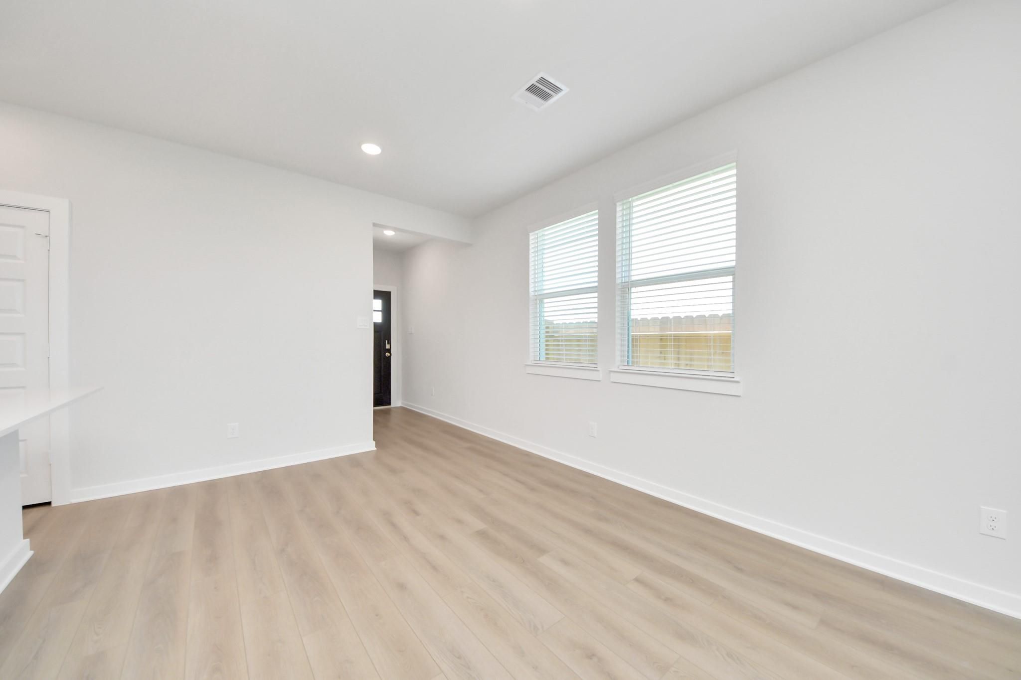 Bright living room with luxury vinyl plank flooring and white walls in Davidson Homes The Costa A plan at Emberly, Beasley, TX