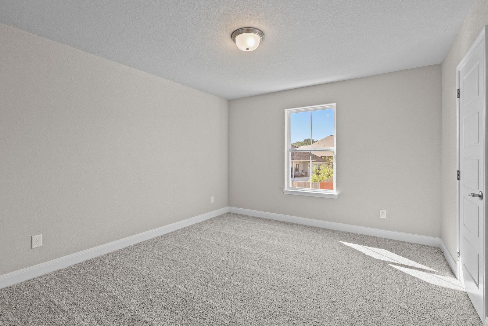 Spacious, carpeted secondary bedroom with neutral walls and natural light in The Jennings G home design.