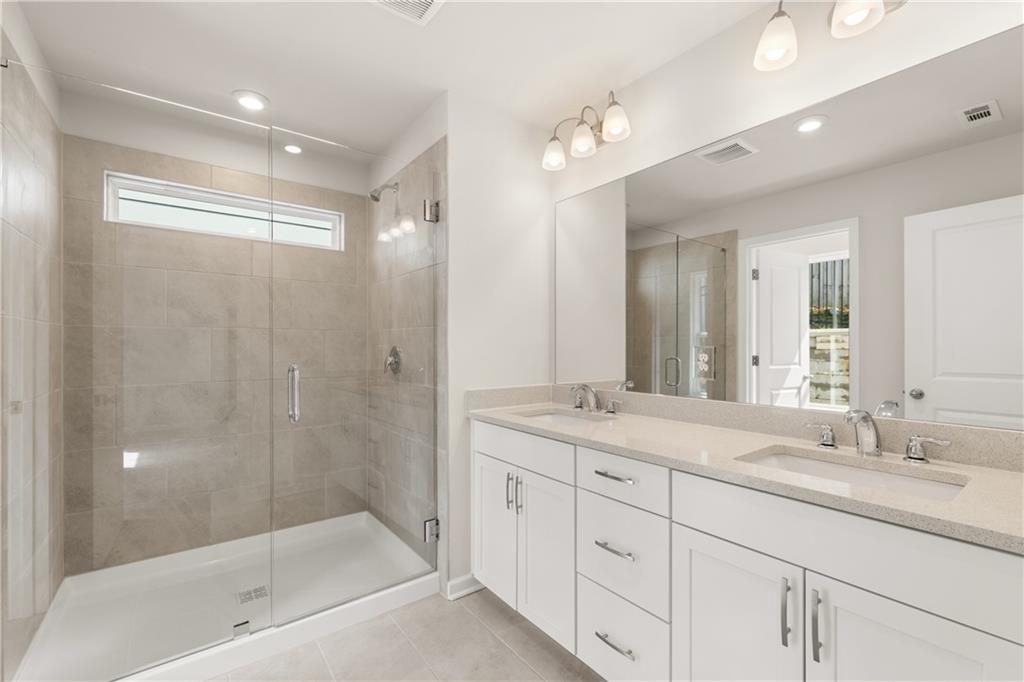 Elegant master bathroom with double vanity, quartz counters, and frameless glass shower in Davidson Homes The Marion B, Kennesaw, GA