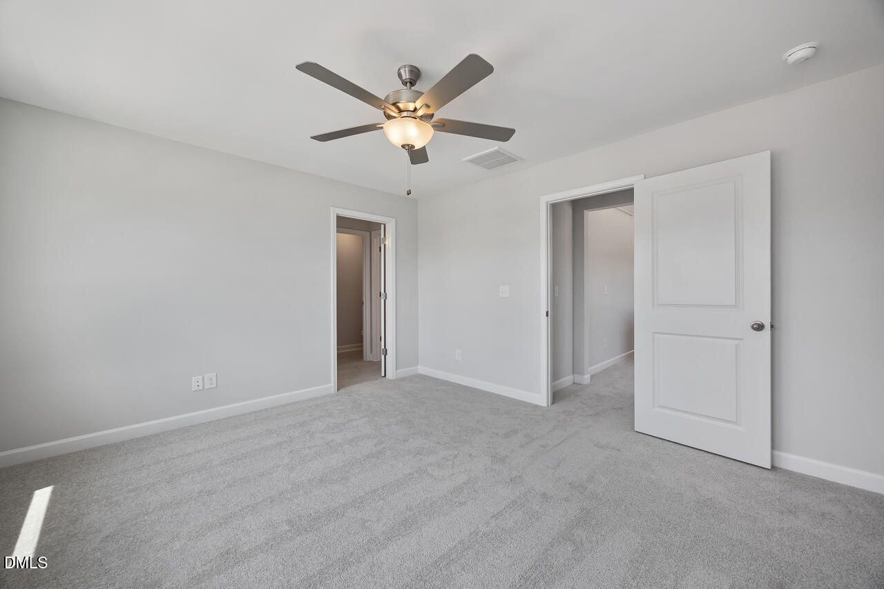 Spacious bedroom with grey carpet and ceiling fan in The Mitchell floor plan at Camden Park, Knightdale, North Carolina.