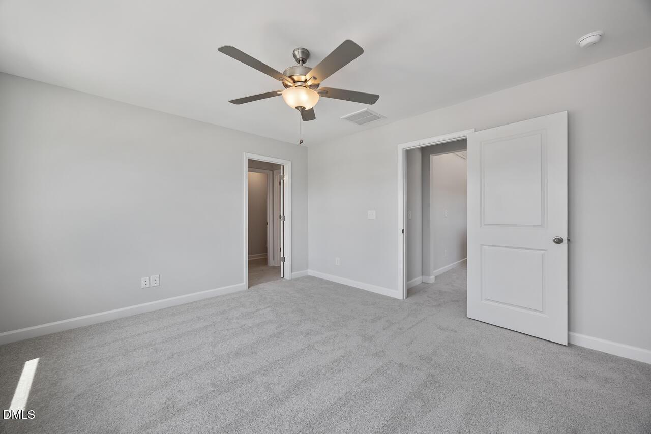 Spacious bedroom with grey carpet and ceiling fan in The Mitchell floor plan at Camden Park, Knightdale, North Carolina.