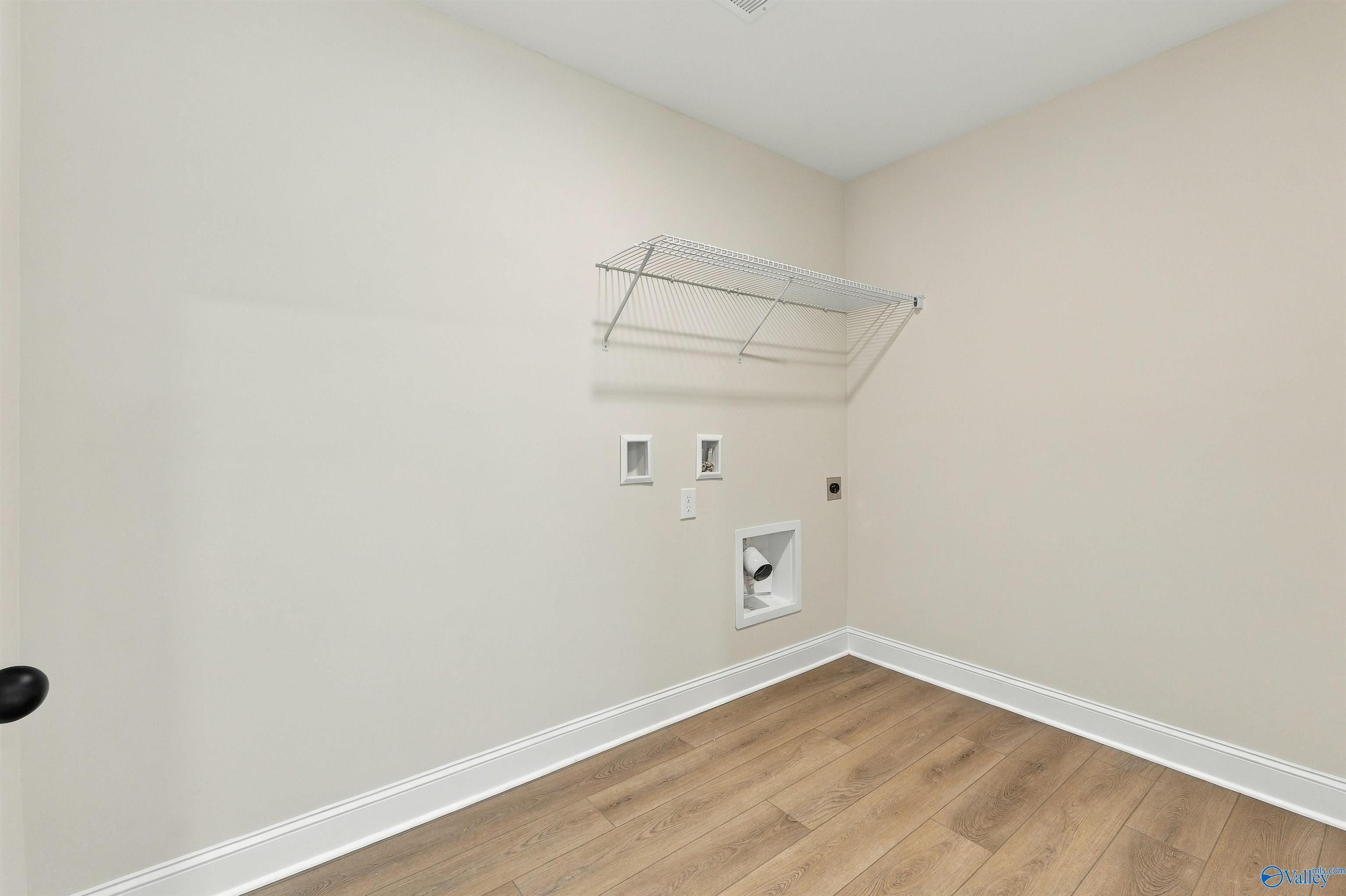 Laundry room with wire shelving, washer hookups, and luxury vinyl plank flooring in Davidson Homes The Shelby A, Athens, Alabama