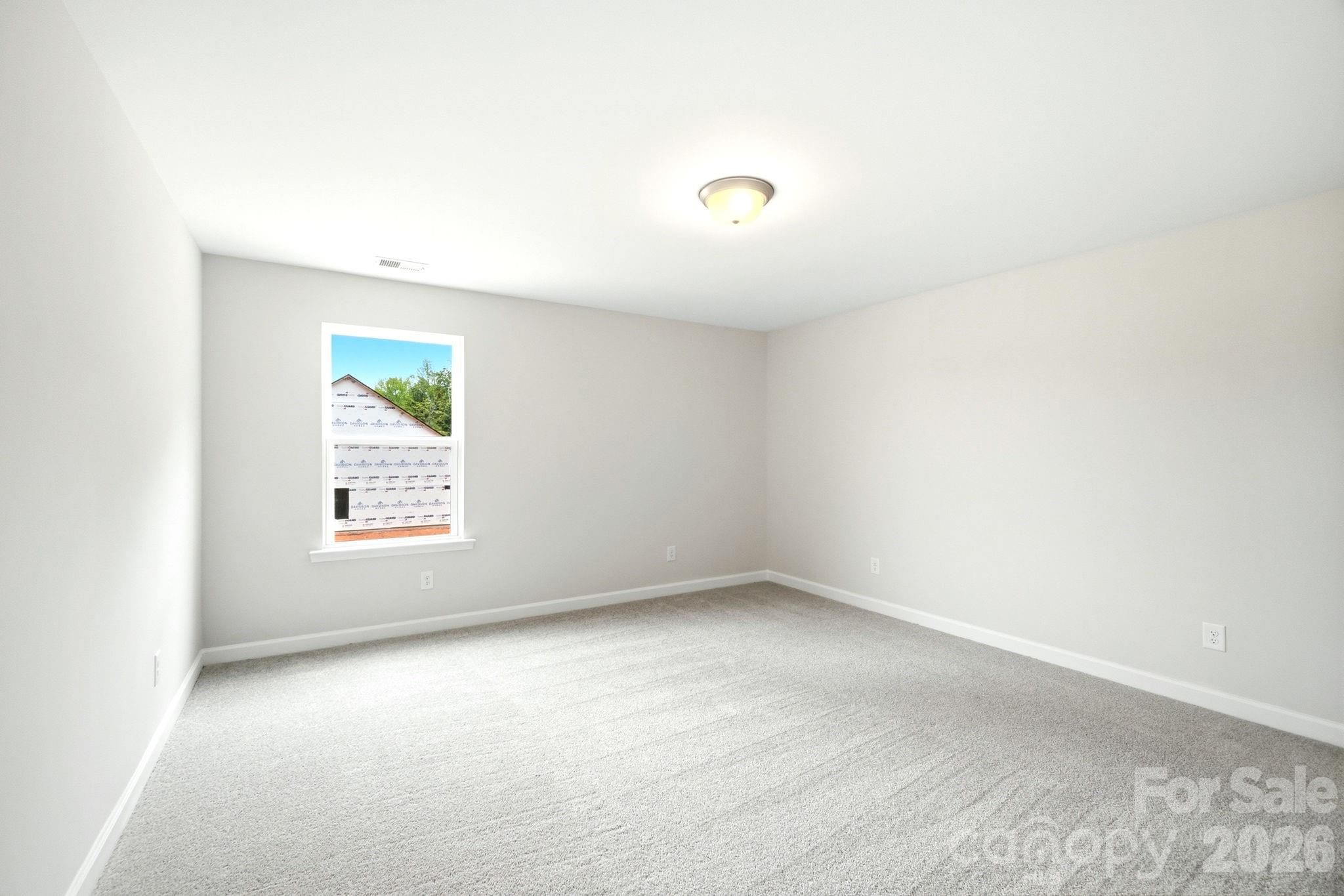 Spacious, carpeted bedroom with neutral walls in The Magnolia B floor plan by Davidson Homes in Windgate, Mooresville, NC.