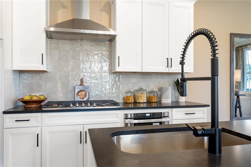 Modern white kitchen with black granite counters, stainless steel appliances, subway tile backsplash in Davidson Homes The Marion B, Kennesaw GA