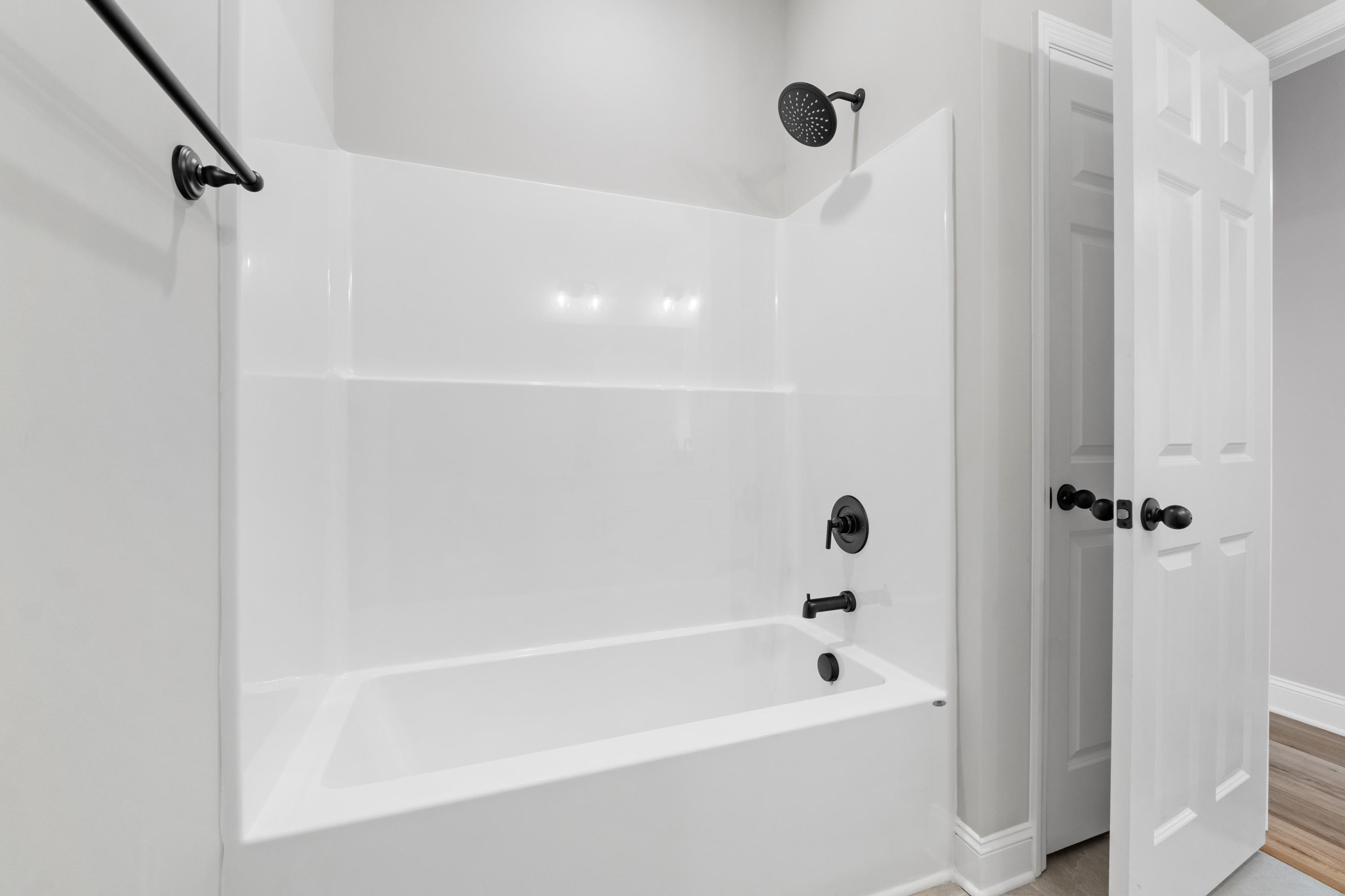 Master bathroom in The Valencia home: white tub, walk-in shower with black fixtures and glass door