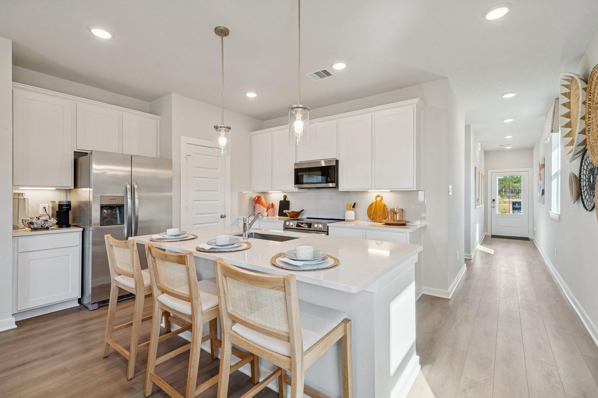 Spacious modern kitchen with white quartz island, stainless appliances, and wooden bar stools at Spring Branch Crossing in Conroe, Texas