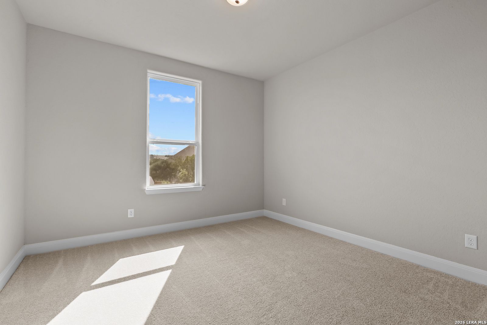 Bright empty bedroom with beige carpet and window in Davidson Homes The Foster E 3-bedroom plan, Potranco Oaks, Castroville, Texas