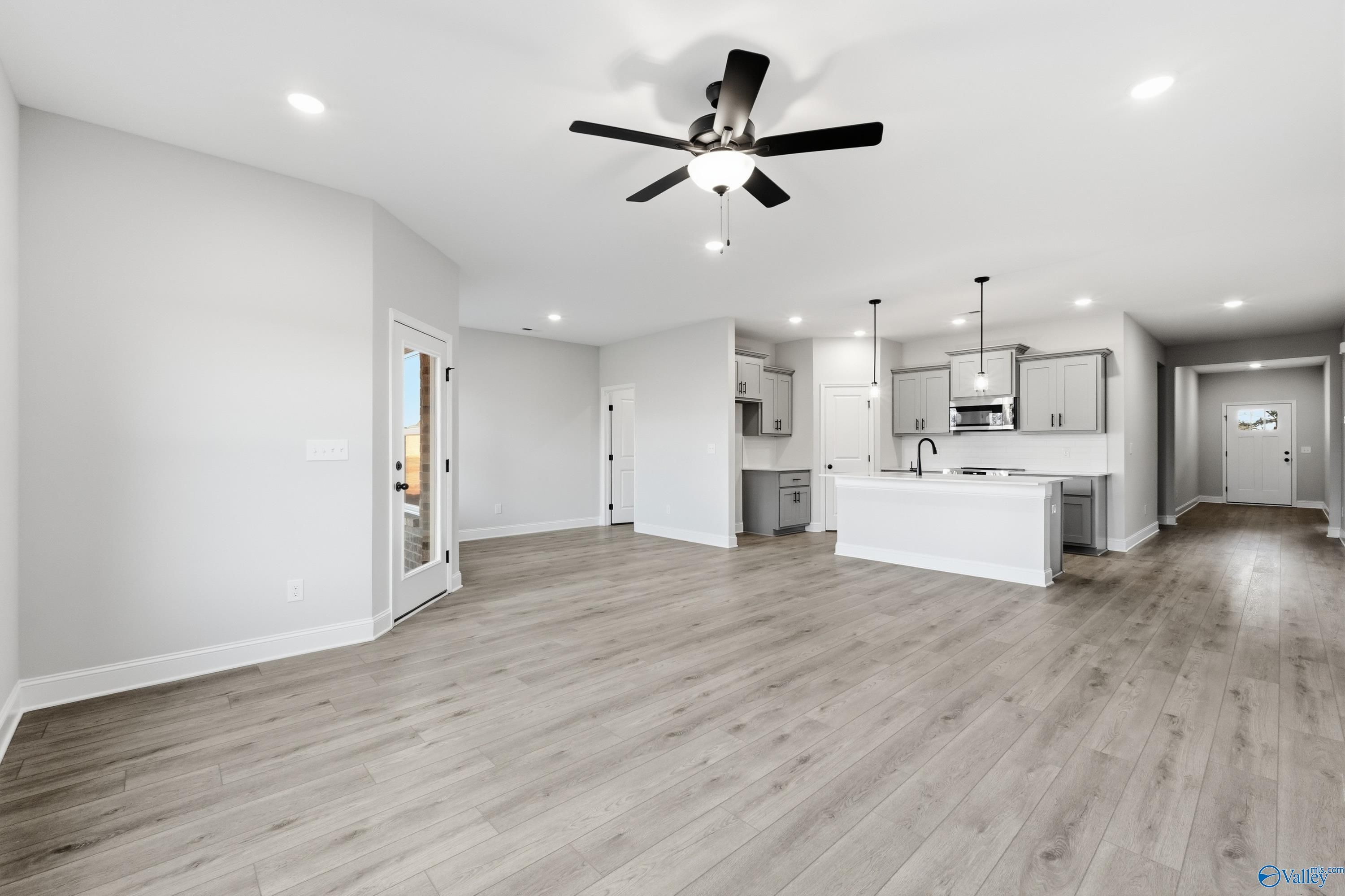 Spacious open-concept kitchen and living room with white cabinets, large island, ceiling fan in The Daphne C, Athens AL