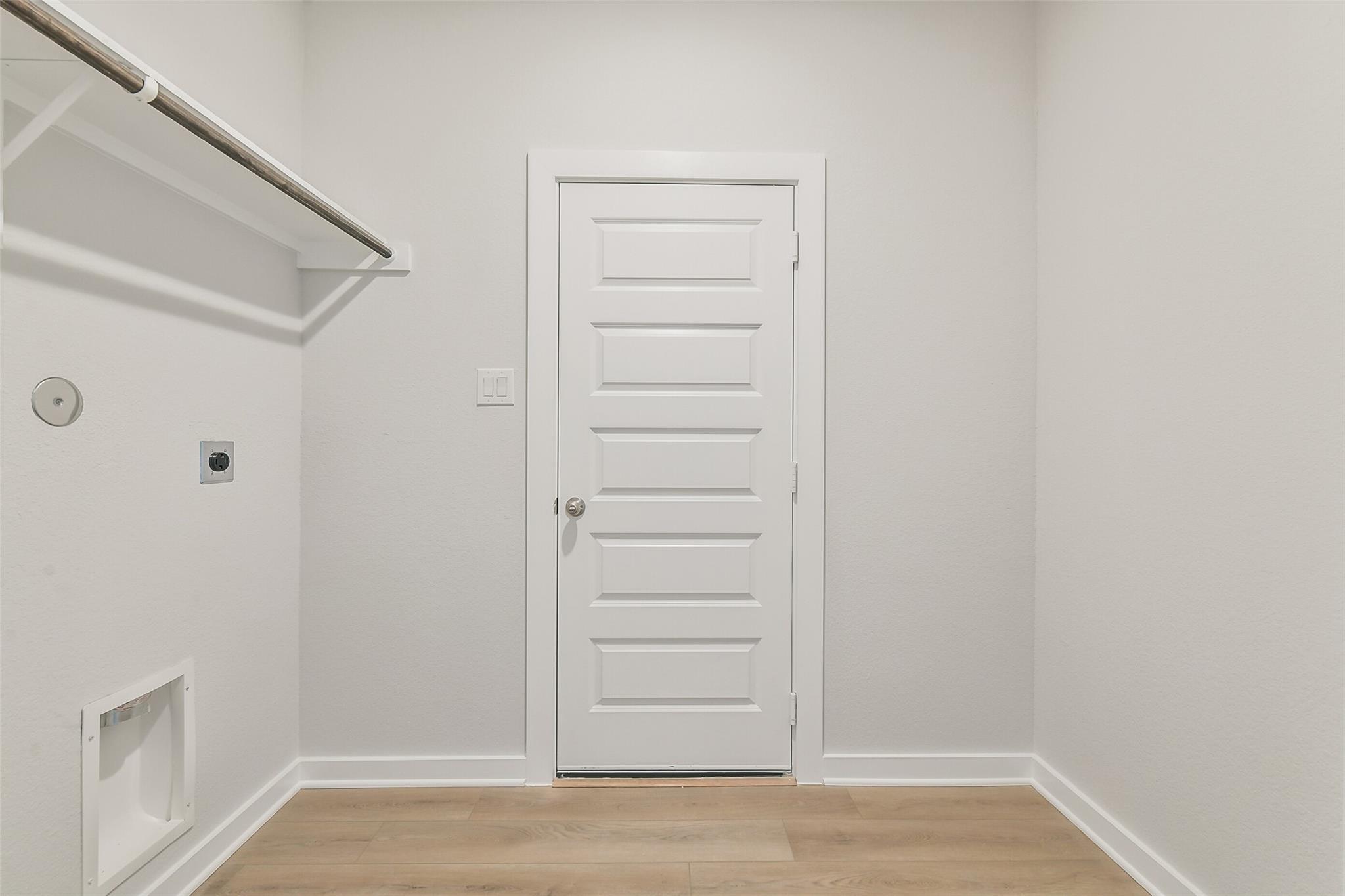 Modern laundry room with hanging rod, washer-dryer outlets, utility vent, and paneled door in Davidson Homes The Frio G, Conroe, Texas