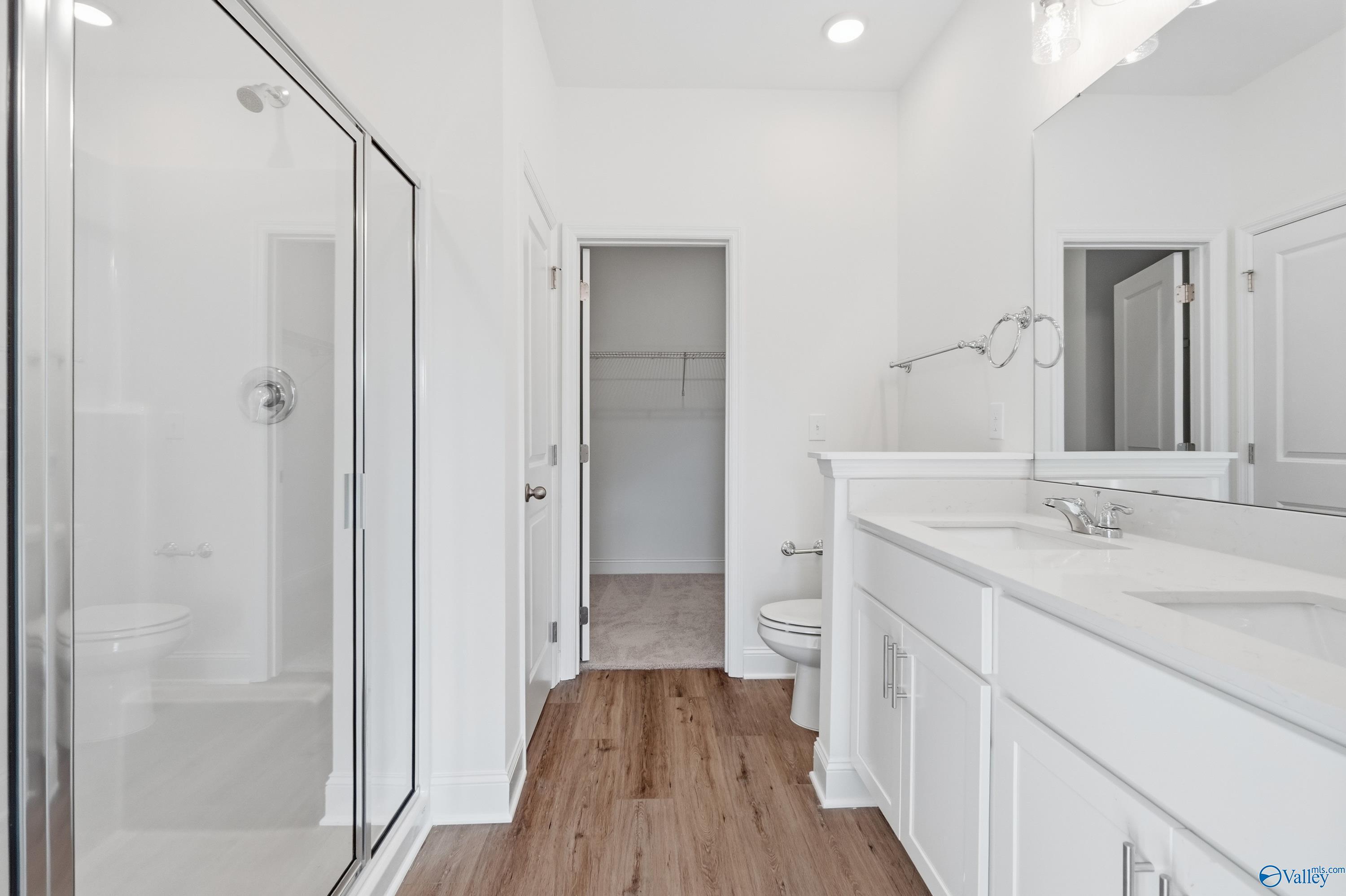 Modern master bathroom featuring frameless glass shower, double vanity, and walk-in closet in The Asheville C by Davidson Homes, Meridianville, AL