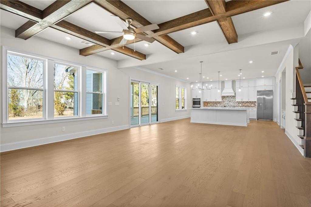 Open-concept living and kitchen with beamed ceiling, hardwood floors, white cabinetry, and sliding doors to backyard in The Arlington A, East Cobb