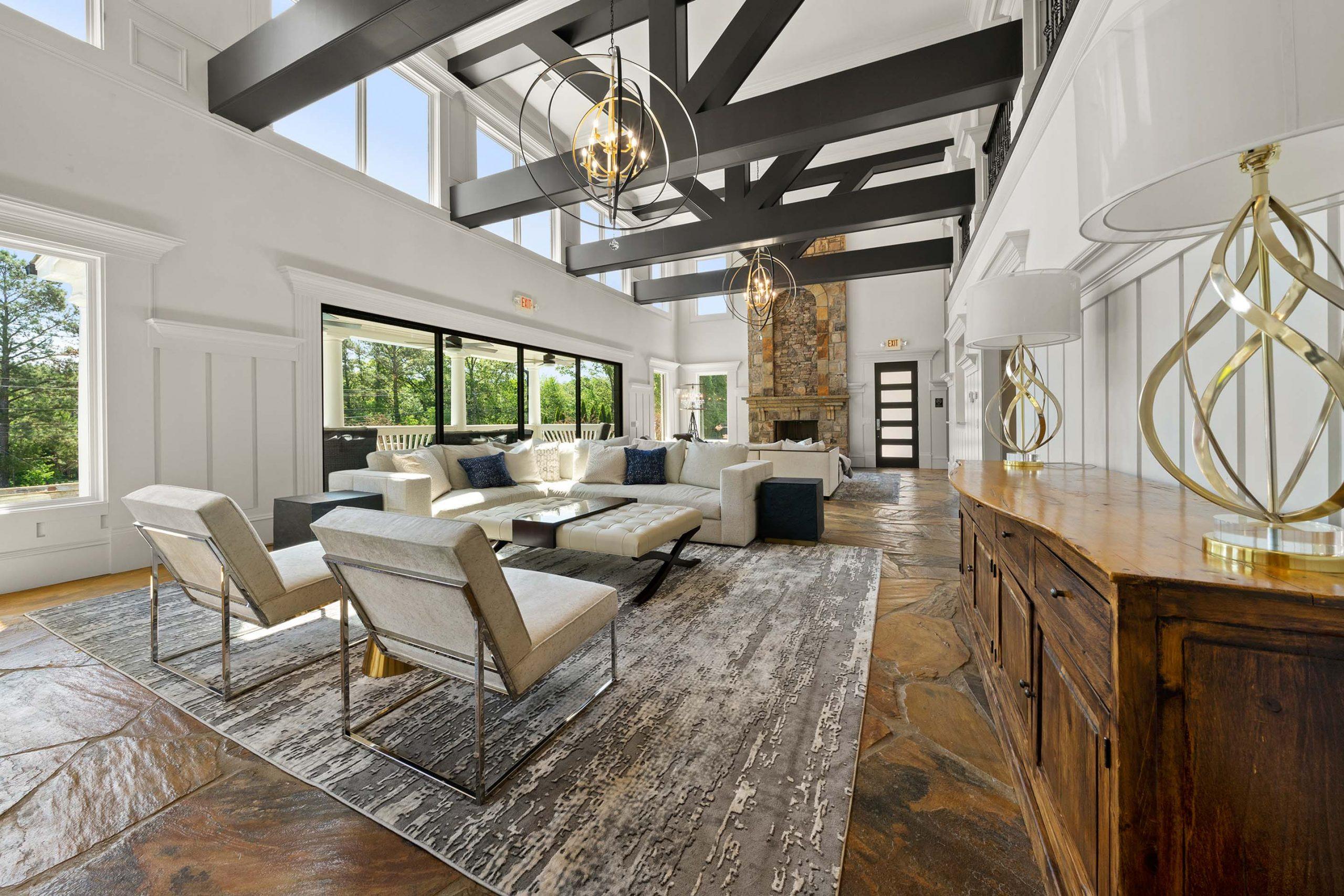 Spacious modern lounge at Mountainbrook in Cartersville, GA with exposed beams, stone fireplace, white sofas, and large windows