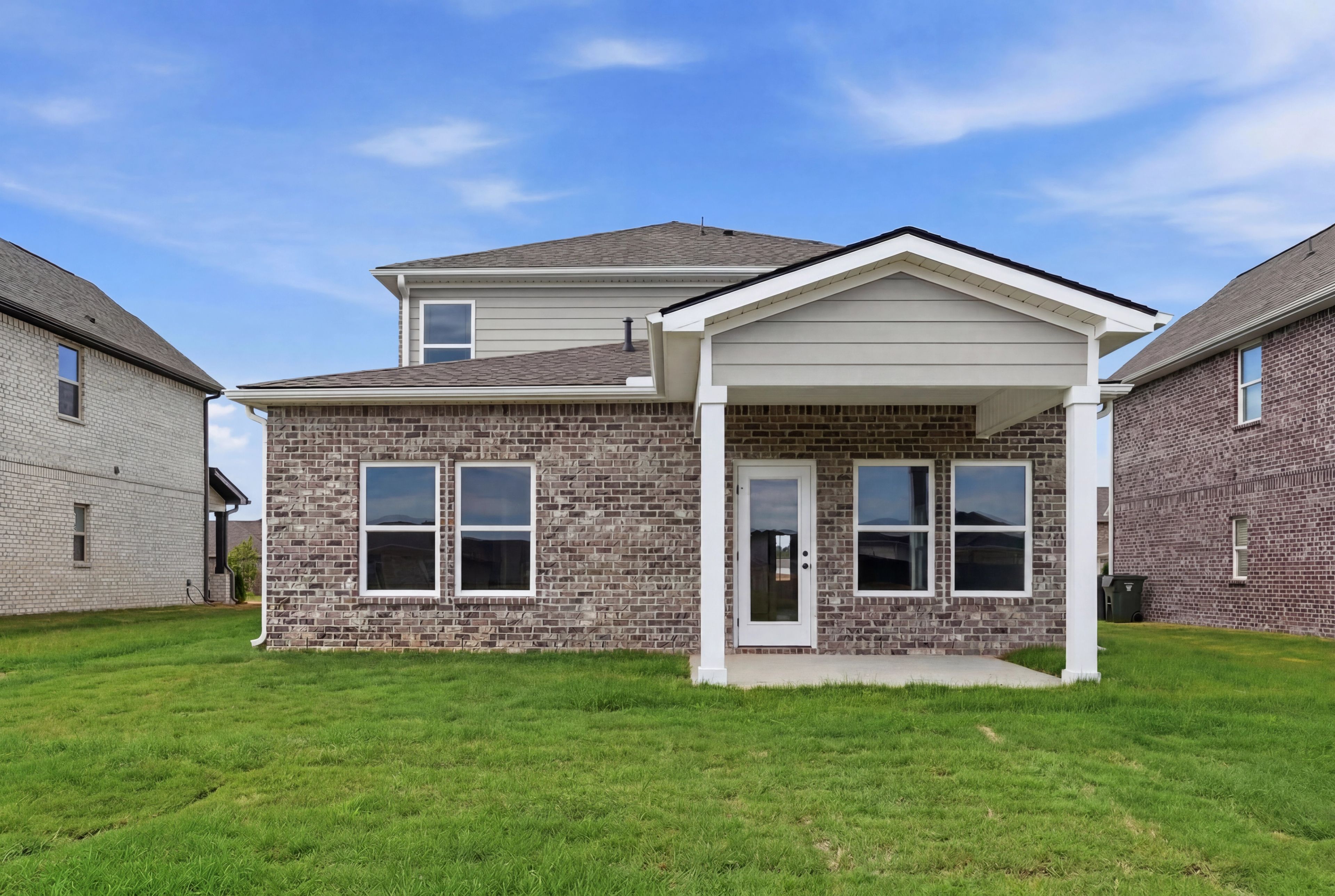 Rear exterior view of The Meadowbrook A single-family home featuring a covered patio and brick and siding facade.