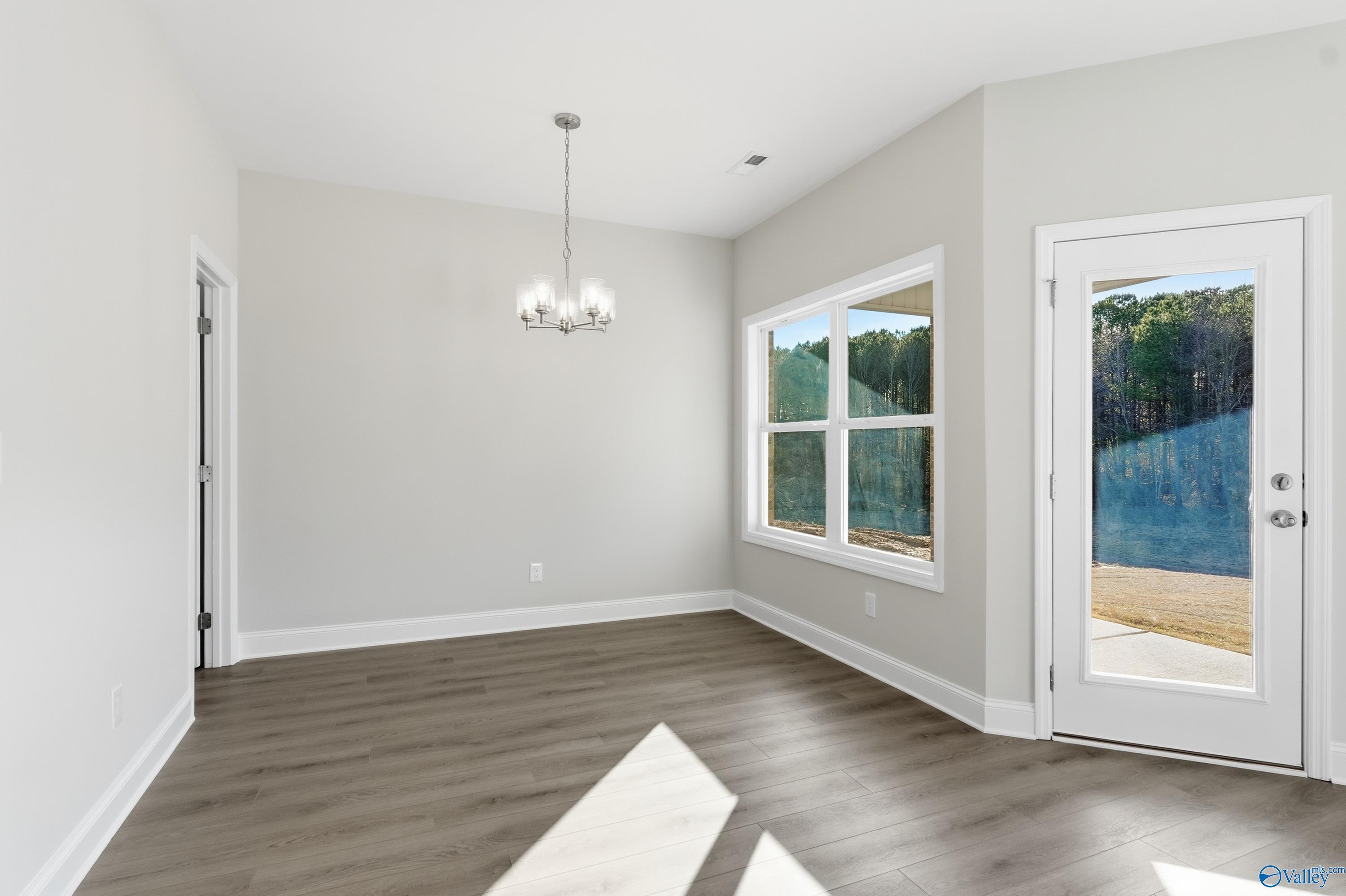 Bright dining nook with chandelier, large windows and glass door to wooded lake view in Davidson Homes The Daphne C, Arab, Alabama