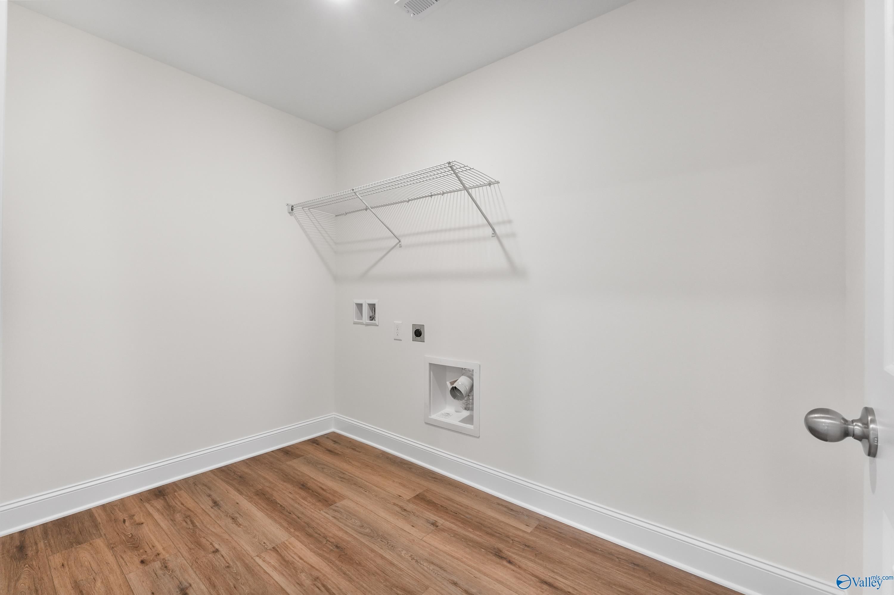 Spacious laundry room with wire shelving, washer-dryer hookups, hardwood floors in The Shelby A by Davidson Homes, Athens, AL