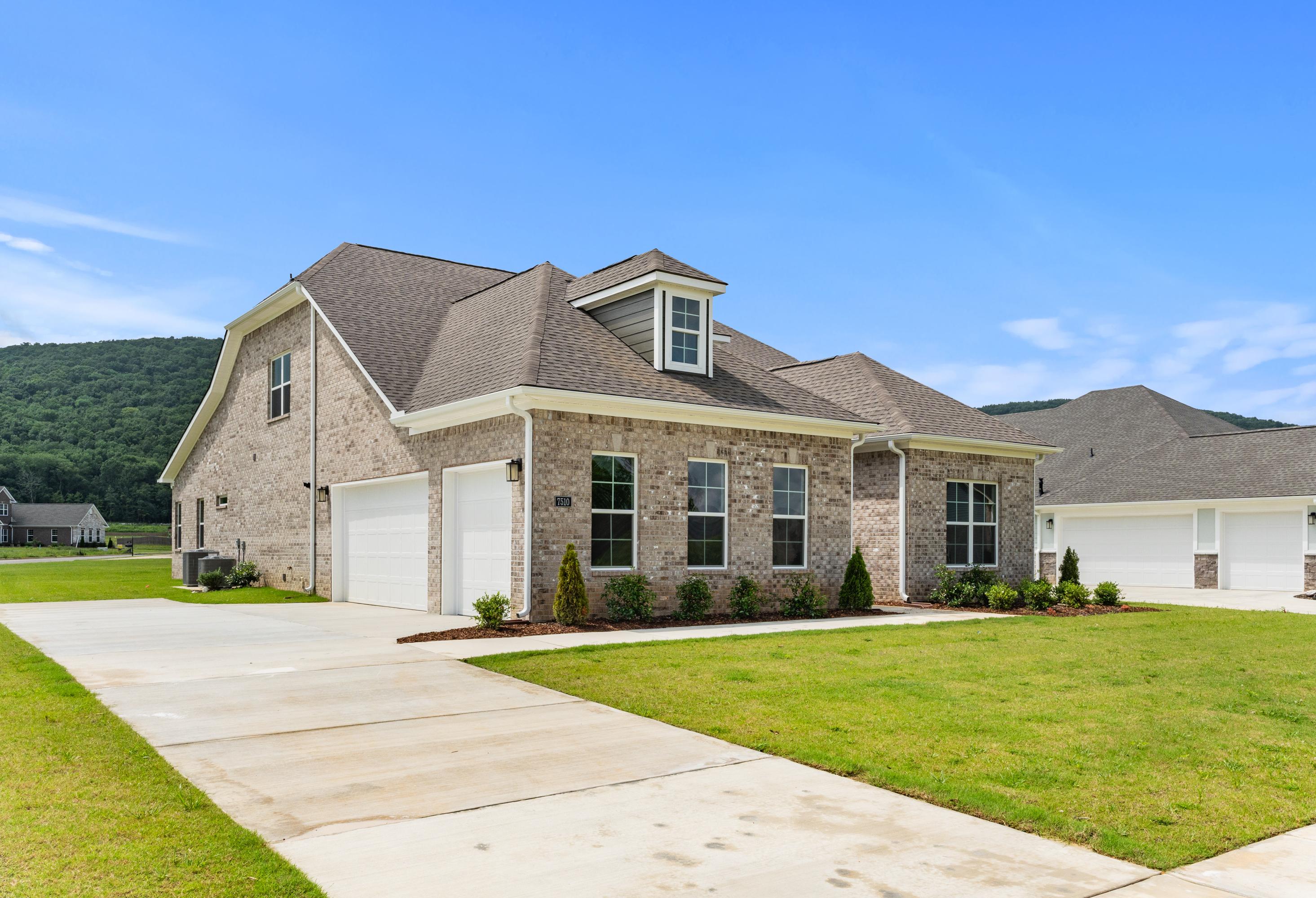 Two-story brick home The Oxford A elevation with 3-car garage, gabled roof, and lush green lawn