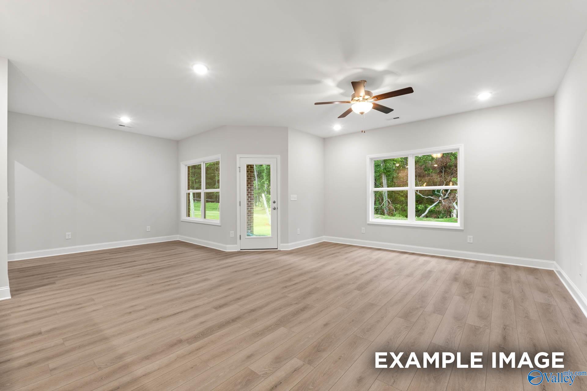 Bright living room with large windows, ceiling fan, and hardwood floors in The Daphne 4-bedroom home, Meridianville, Alabama