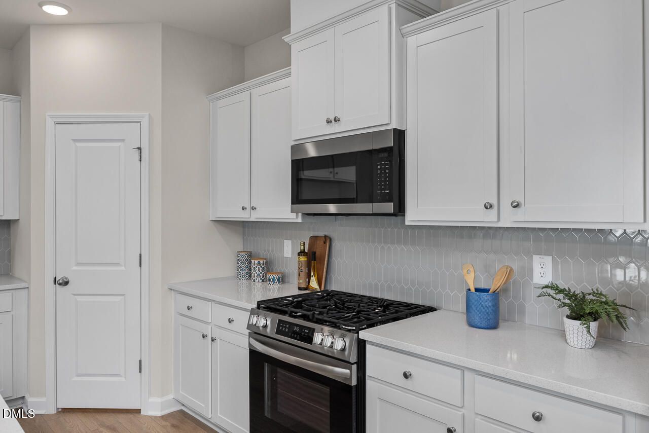 Modern kitchen with white shaker cabinets, stainless steel gas range, oven, microwave, subway tile backsplash in The Preston A, Lillington, NC