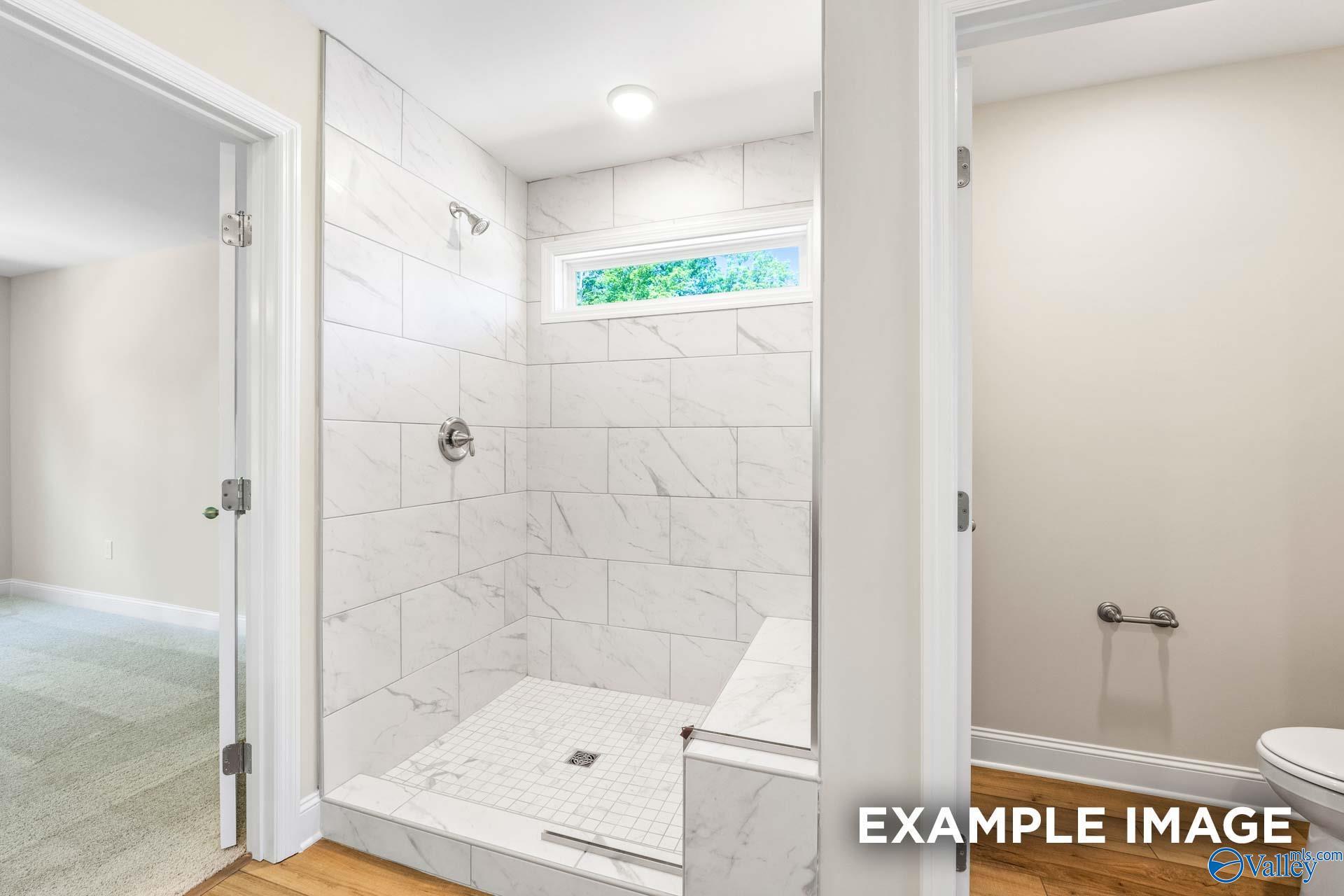 Elegant walk-in shower with white subway tiles, frameless glass door, and clerestory window in master bath of Davidson Homes The Shelby B, Owens Cross Roads, AL