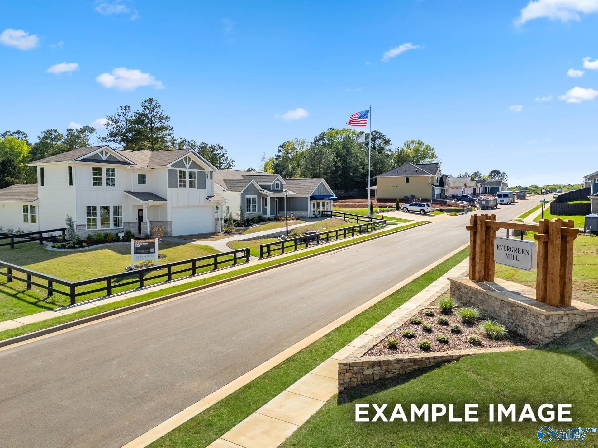Evergreen Mill neighborhood entrance with modern 2-story white homes, American flag, black fencing in Madison, Alabama by Davidson Homes