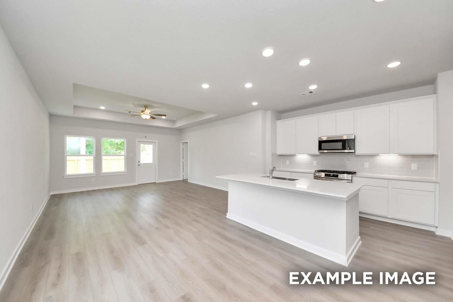 Open-concept kitchen with white cabinetry, center island, and stainless appliances in Davidson Homes The Blanco E, Magnolia, TX