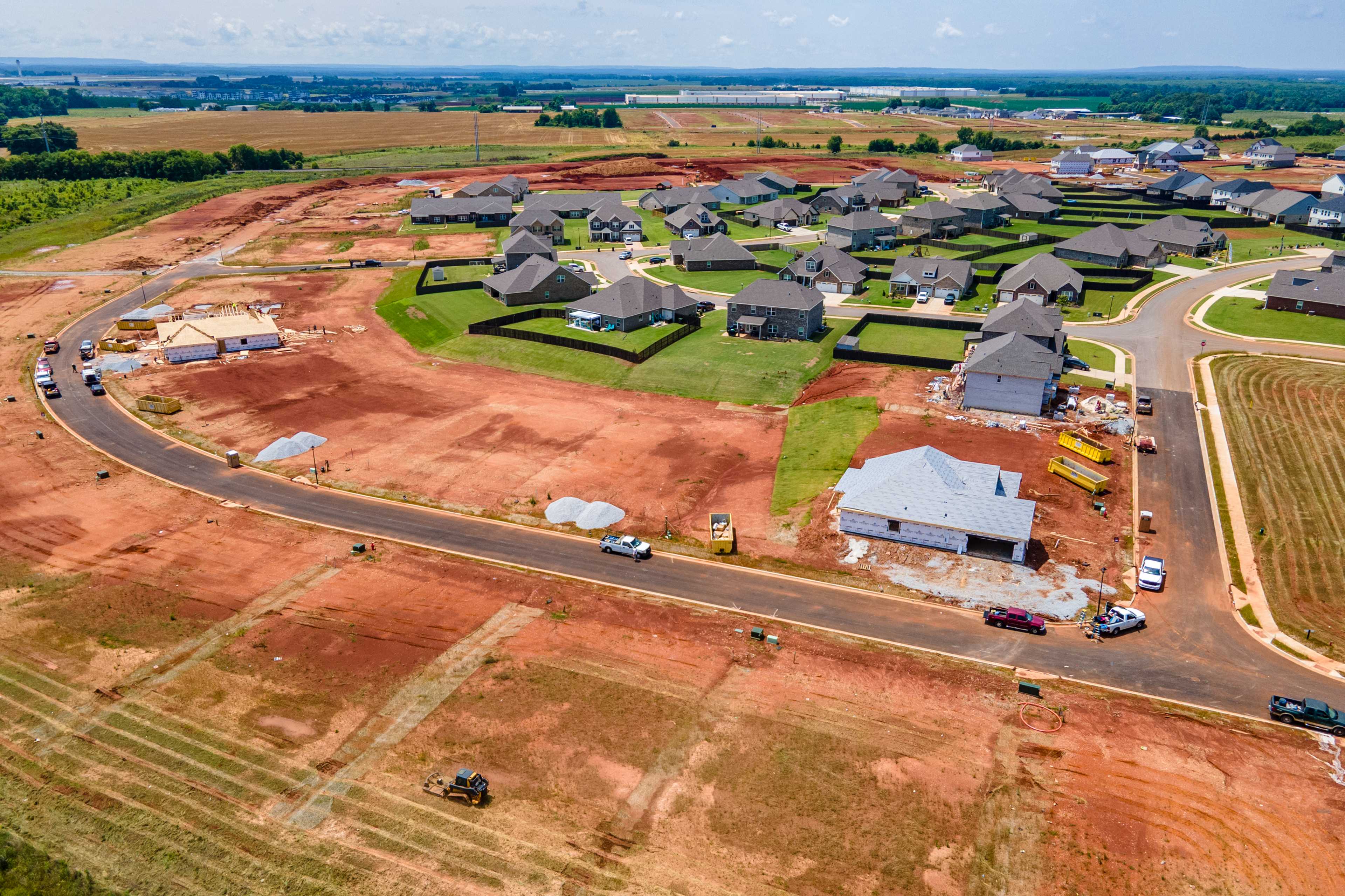 Aerial view of Barnett's Crossing new home construction in Madison Alabama with gabled roof houses, dirt roads, and farmland