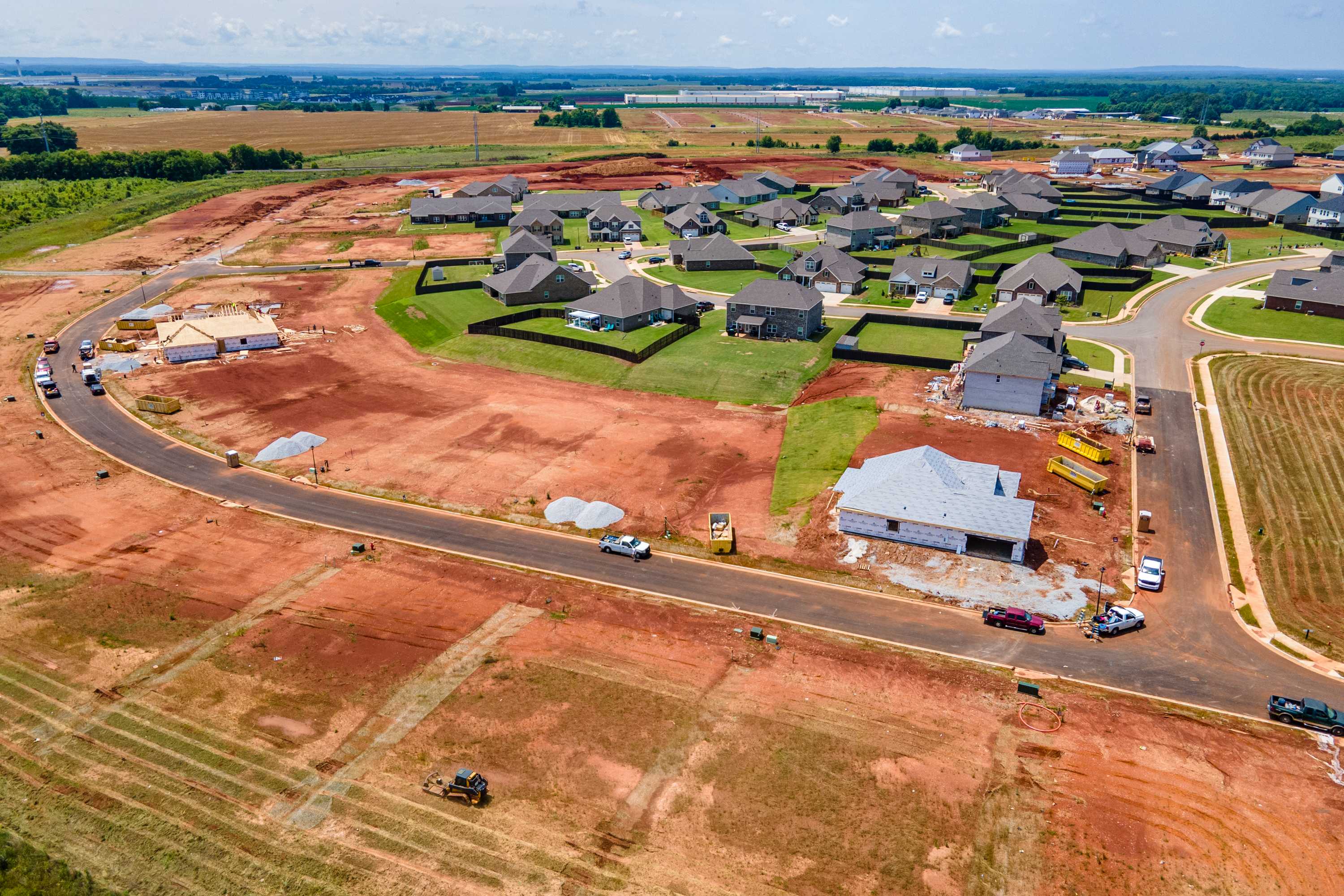Aerial view of Barnett's Crossing new home construction in Madison Alabama with gabled roof houses, dirt roads, and farmland