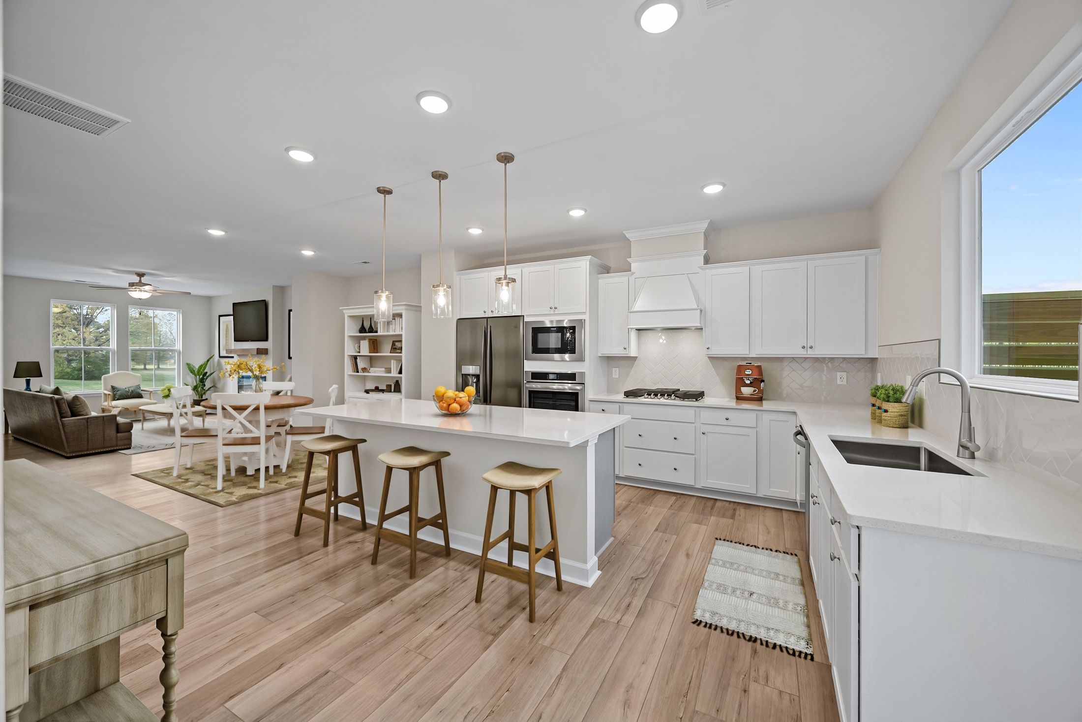 Open-concept kitchen at Forestville Yard Townhomes in Knightdale NC featuring white cabinets, quartz island with bar stools, and hardwood floors