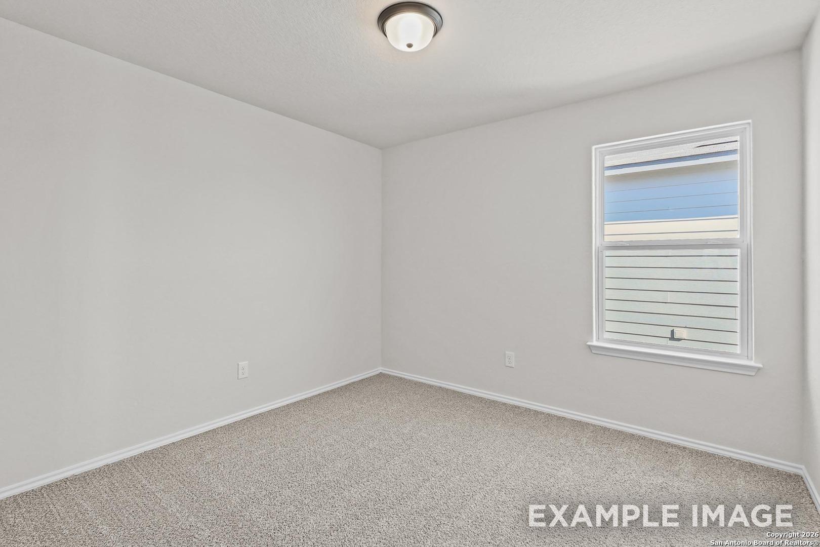 Bright empty bedroom with neutral walls, beige carpet, ceiling light, and window blinds in Davidson Homes The Trinity B, San Antonio TX