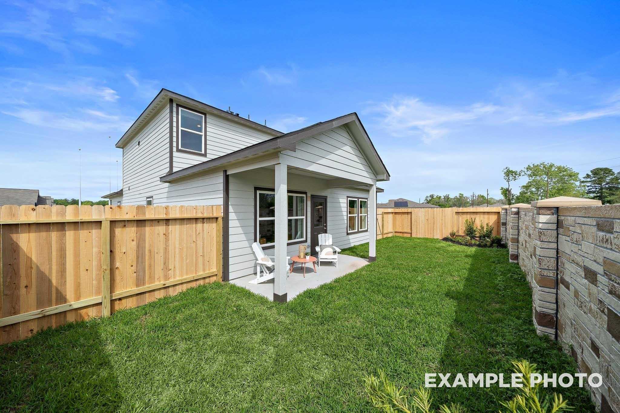 Two-story Sabine F home exterior with covered porch, white chairs, and lush fenced backyard in Windmill Estates, Magnolia, Texas